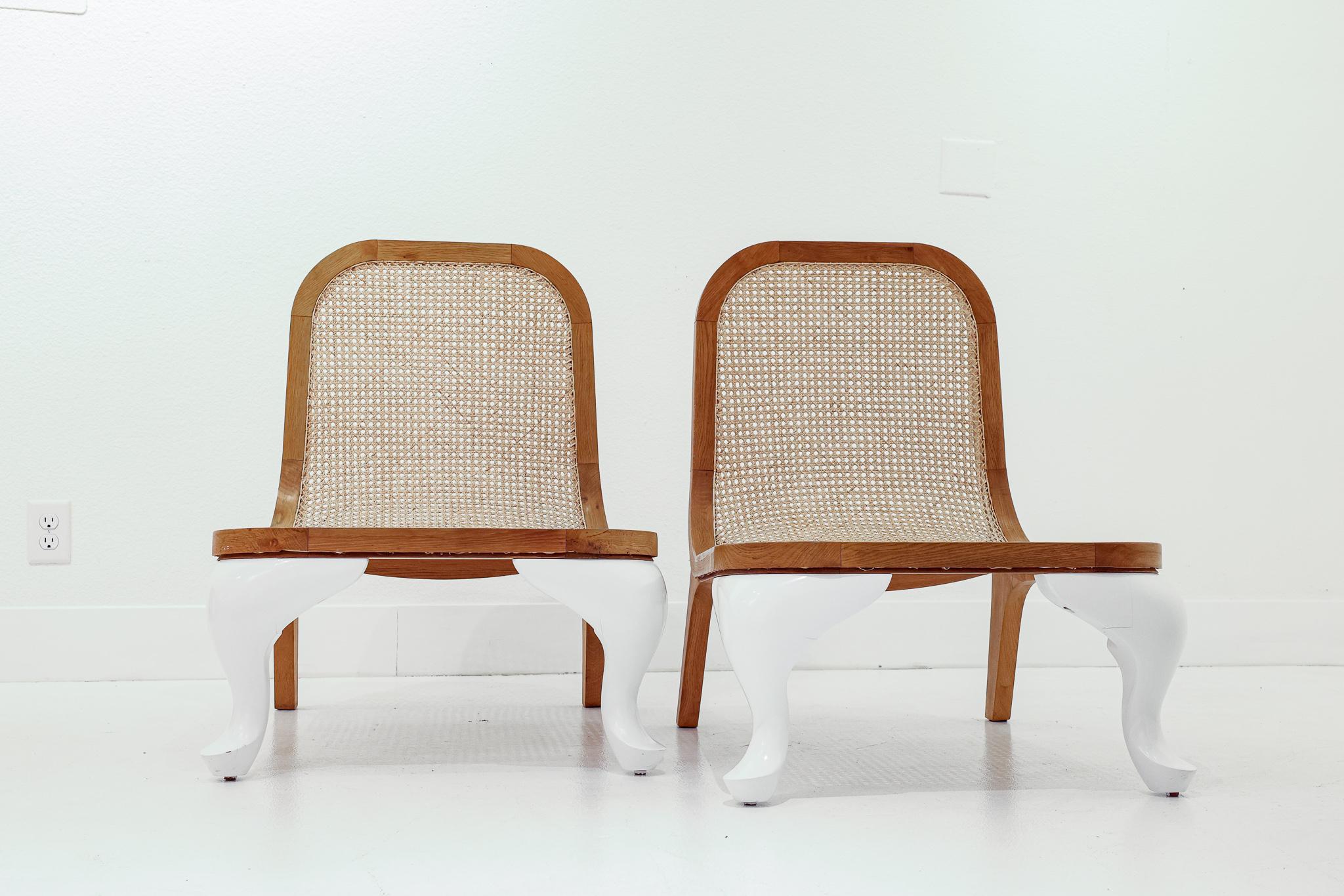 This is a unique pair of caned and lacquered slipper chairs. Their low profile, caning, and lacquered legs makes these chairs irresistible. Made of oak, the frame surrounds the seat and the back rest; the rear legs have a horizontal support and are
