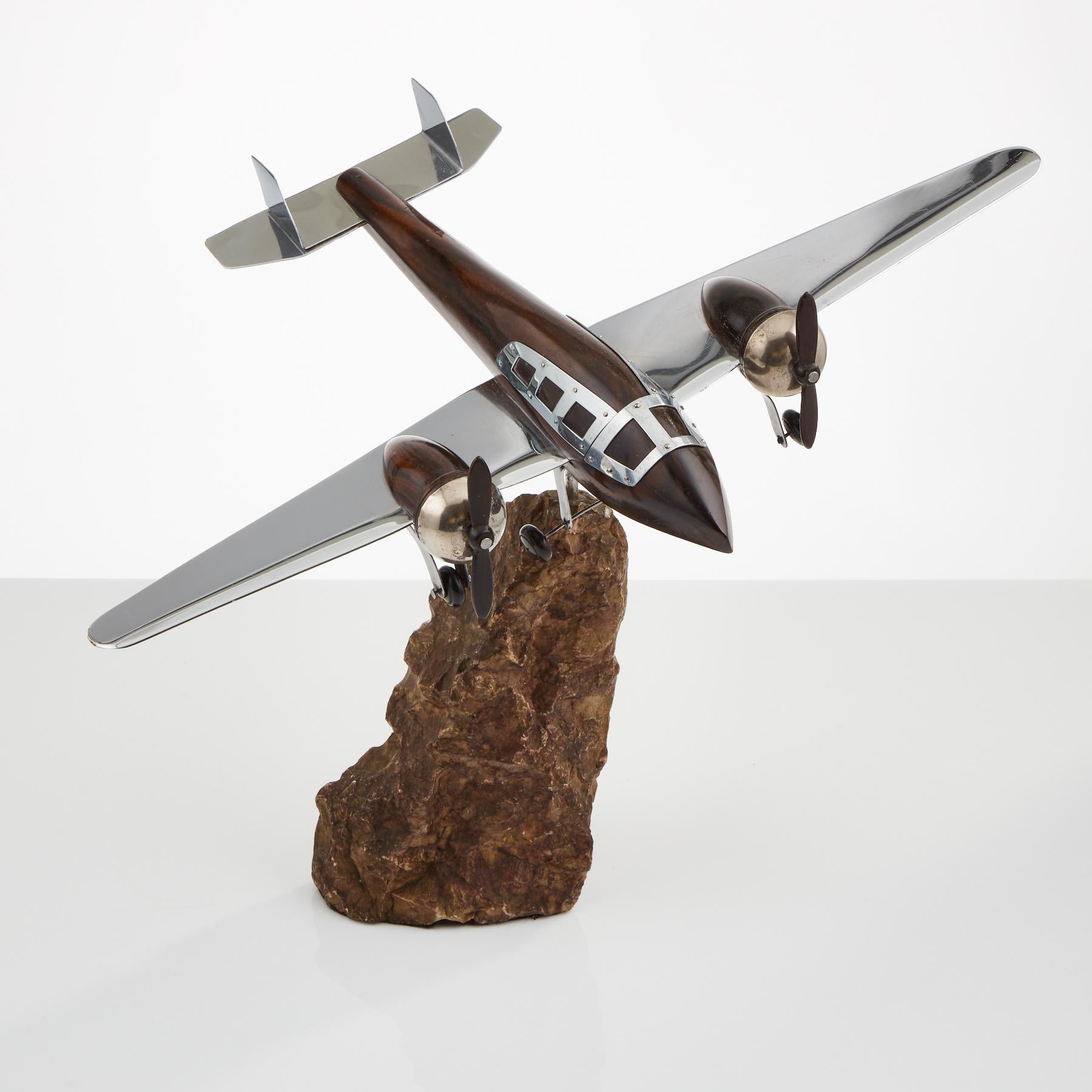 A unusual French Art Deco model of an aircraft, circa 1940.
The body, engine casing & propellers are made of Macassar wood. 
The wings, tail & cockpit are metal with a chrome finish. 
The rocky display base appears to be granite & the plane is
