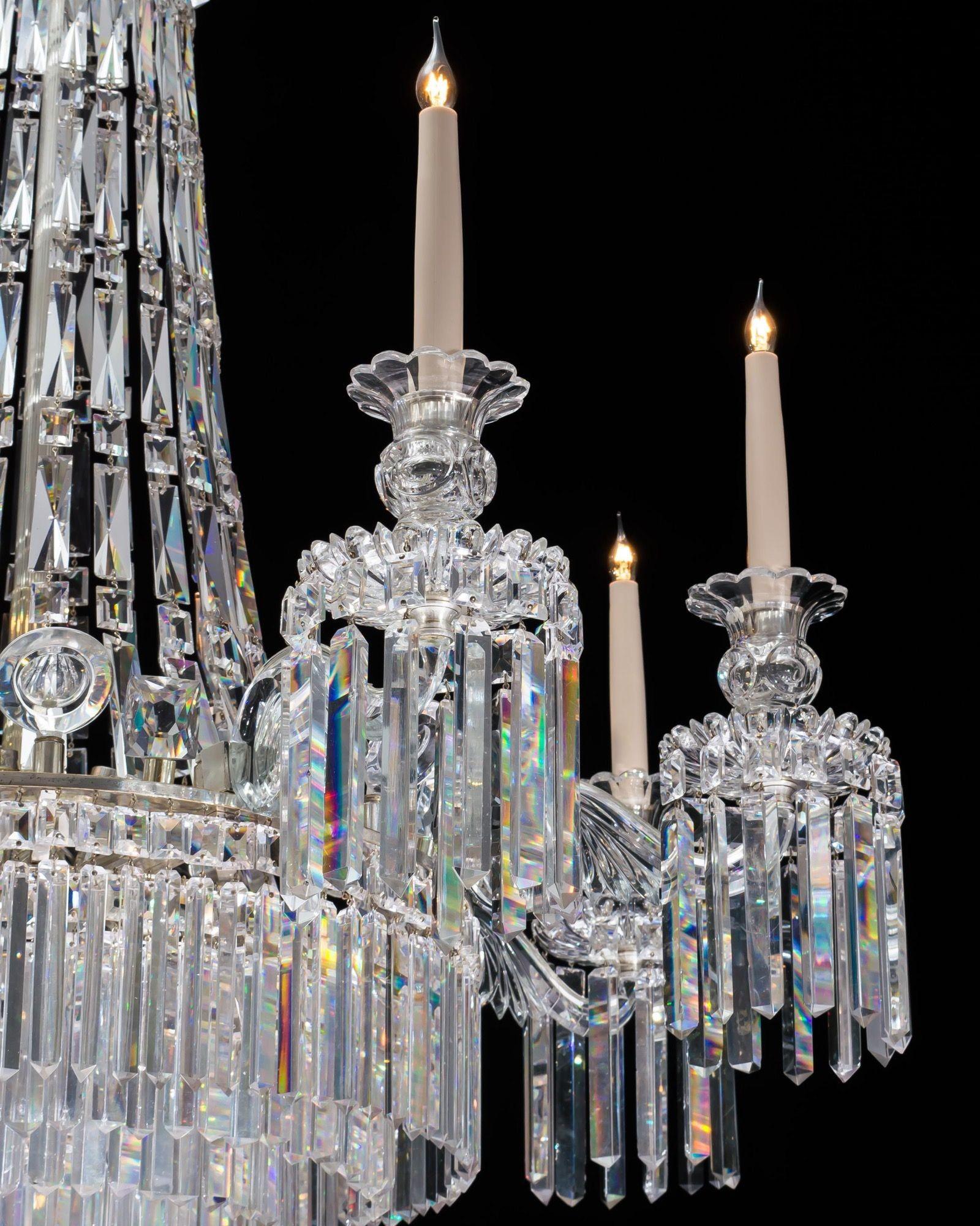 La corona appesa a goccia sostiene catene a cascata di tende prismatiche fino all'anello principale, questo montato con occhio di bue e finali a forma di soldato, l'anello che emette otto bracci foliati che sostengono gocciolatoi a taglio radiale e