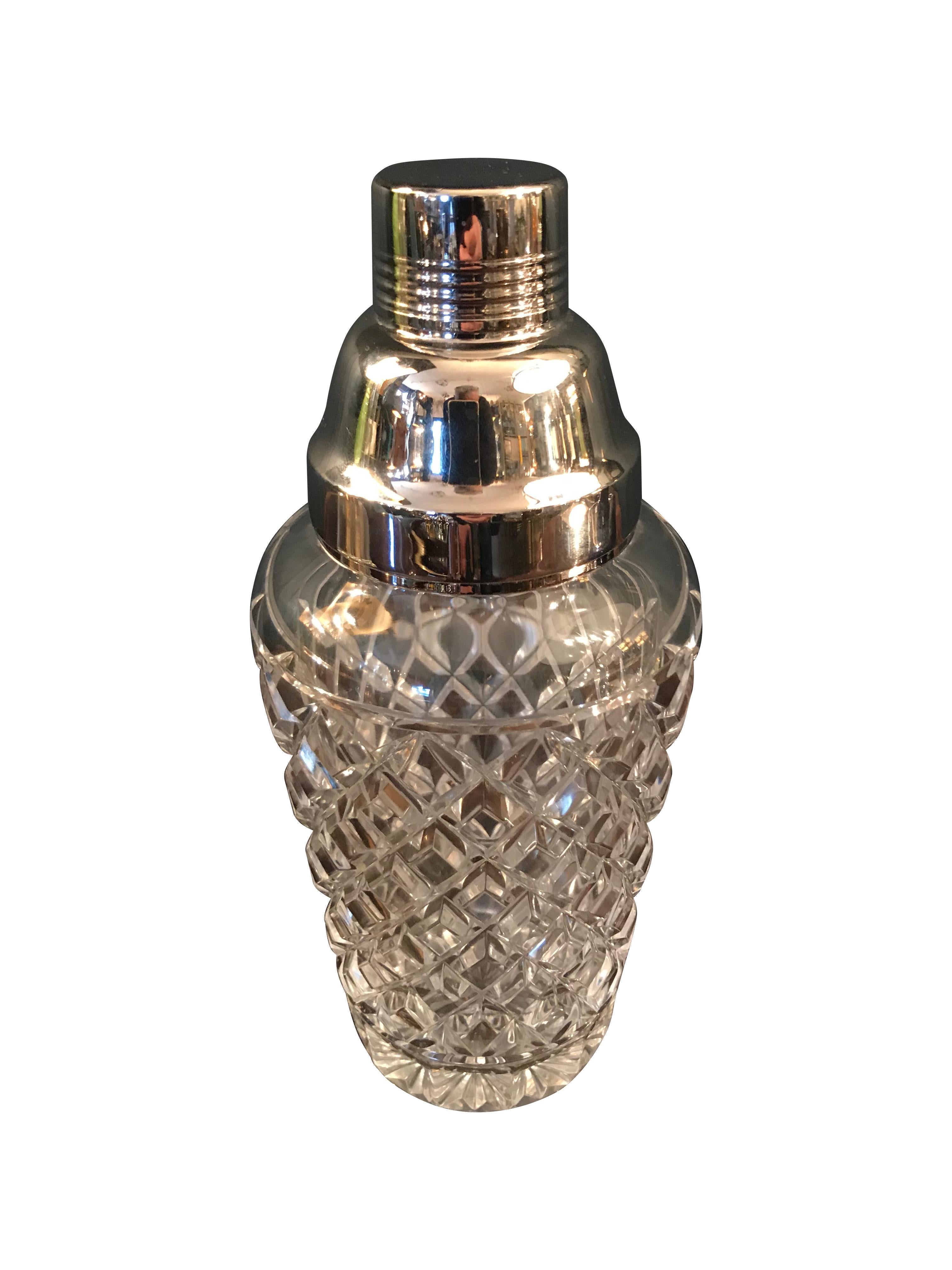 A Val St Lambert rhodium plated and crystal glass cocktail Shaker with diamond faceted detail. The top separates into two parts with a lid and stainer top that fits onto the metal rim. 

Rhodium is a rare and precious element that can be 10 to 25