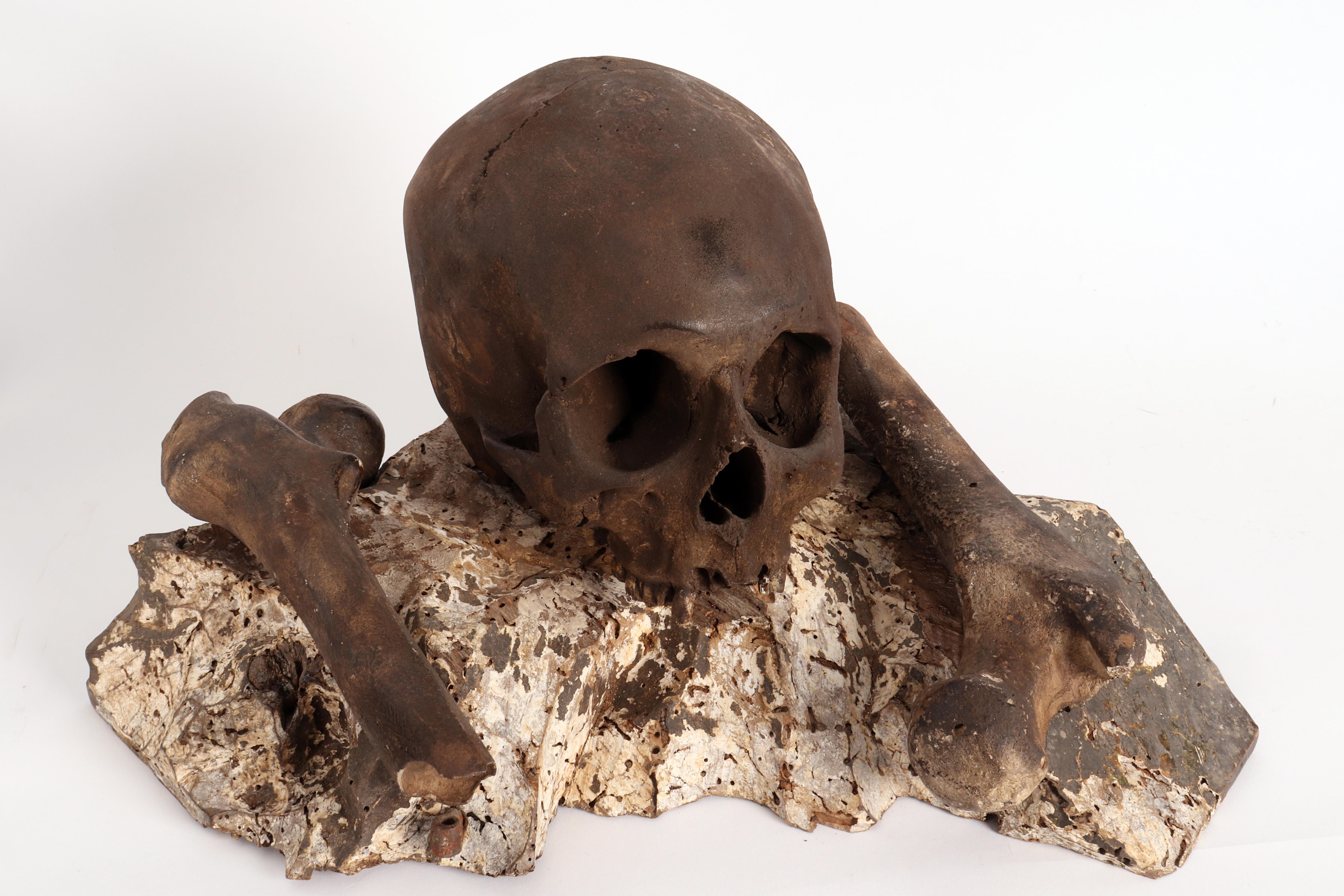 Over the carved wooden painted base depicting a rock, is set a Vanitas, plaster cast sculpture of a human skull, with femoral bones. Italy last part of 18th century.