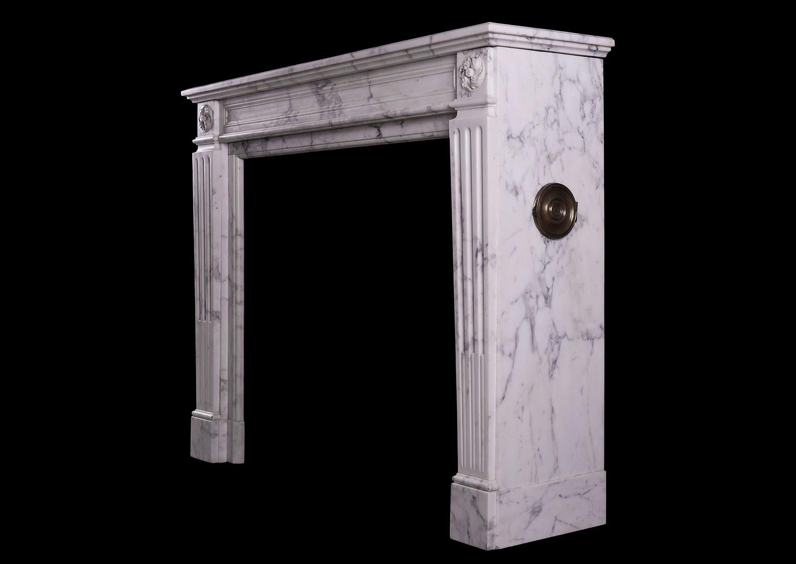 A French Louis XVI style veined statuary marble fireplace. The stop fluted jambs surmounted by carved swirling paterae. The panelled frieze with moulded shelf above, circa 1860.

Measures: 
Shelf width: 1350 mm / 53 1/8 in
Overall height: 1085 mm /