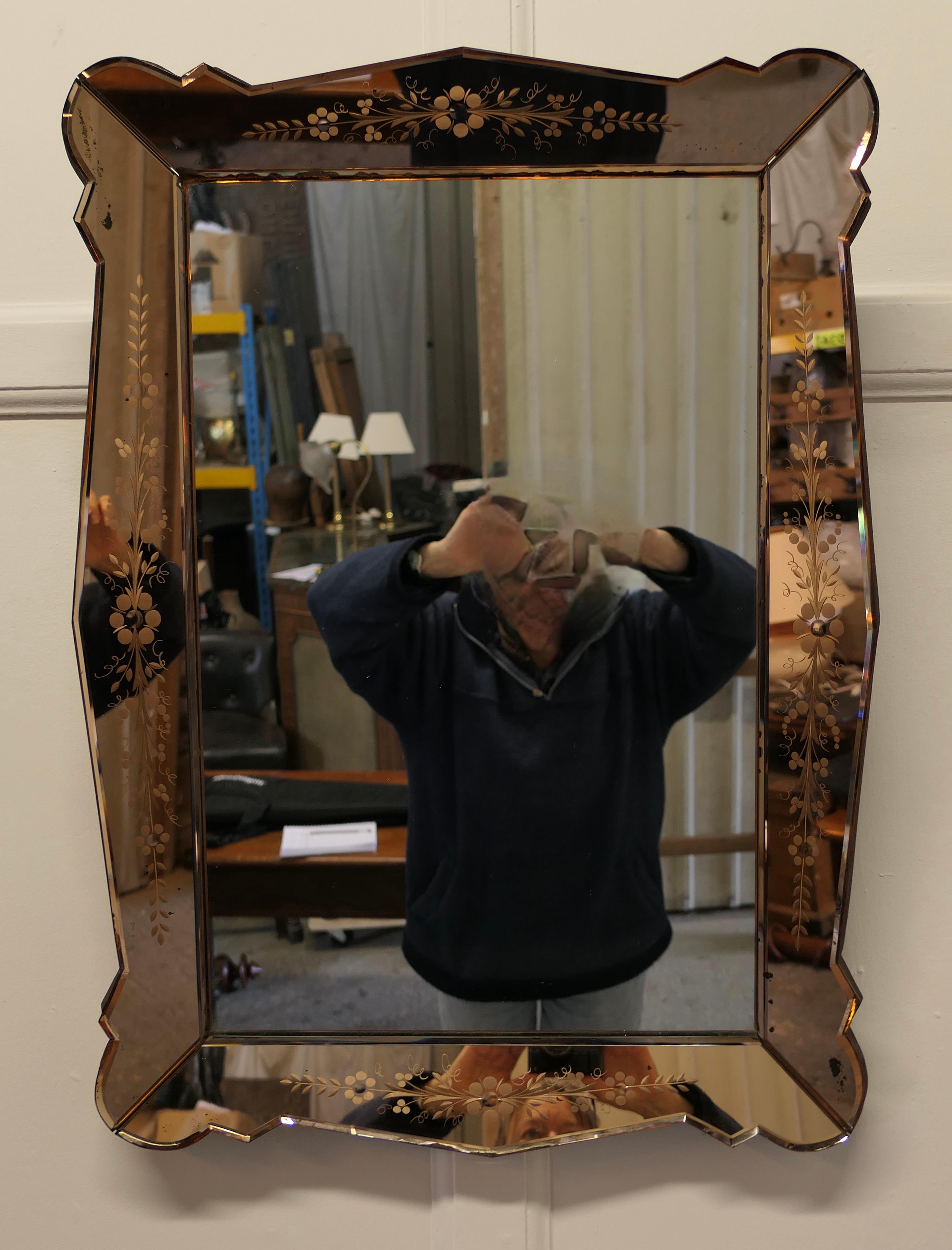 A Venetian Etched Art Deco Wall Mirror.

This attractive piece has a central rectangular mirror and is framed with 3” pink mirrors which have scalloped edges and are decorated with a floral design 
The mirror is in good condition, there is minor