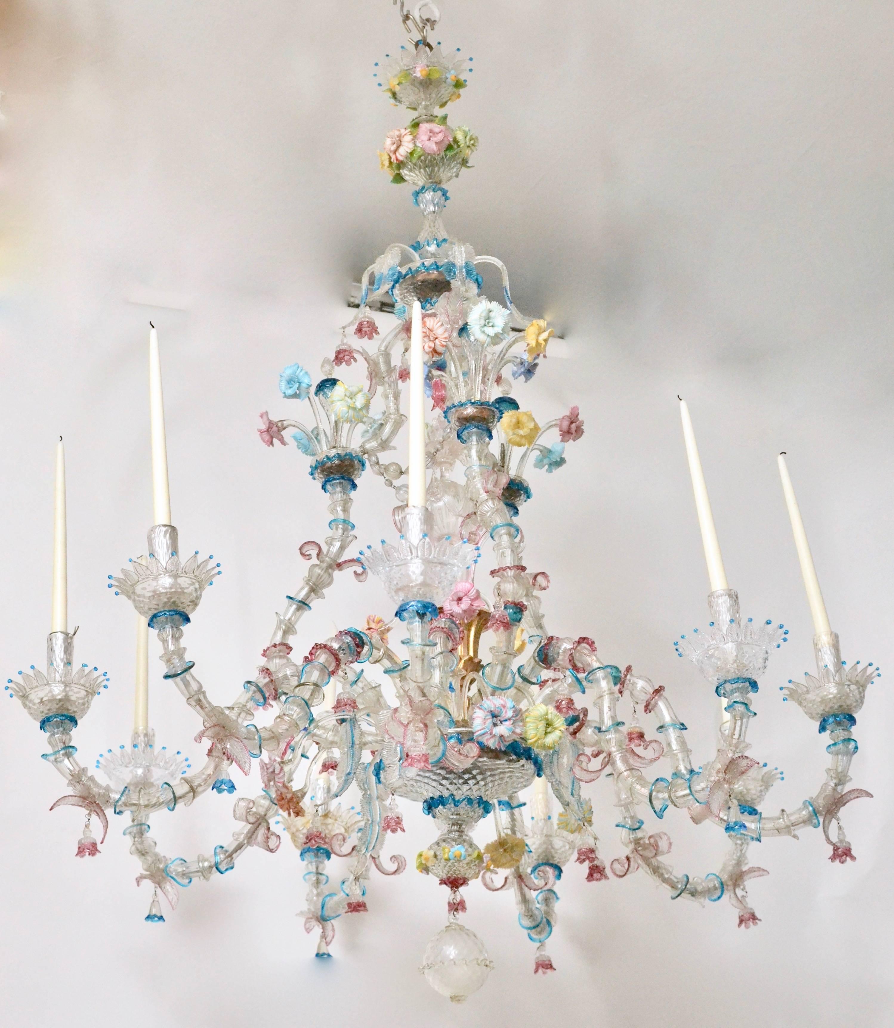 Un grand lustre à huit lumières en verre de Murano polychrome vénitien du 19ème siècle avec des bras de bougies à volutes, décorés de fleurs et de feuilles. 

Les lustres en verre de Murano ont une histoire unique qui est liée à leur emplacement.