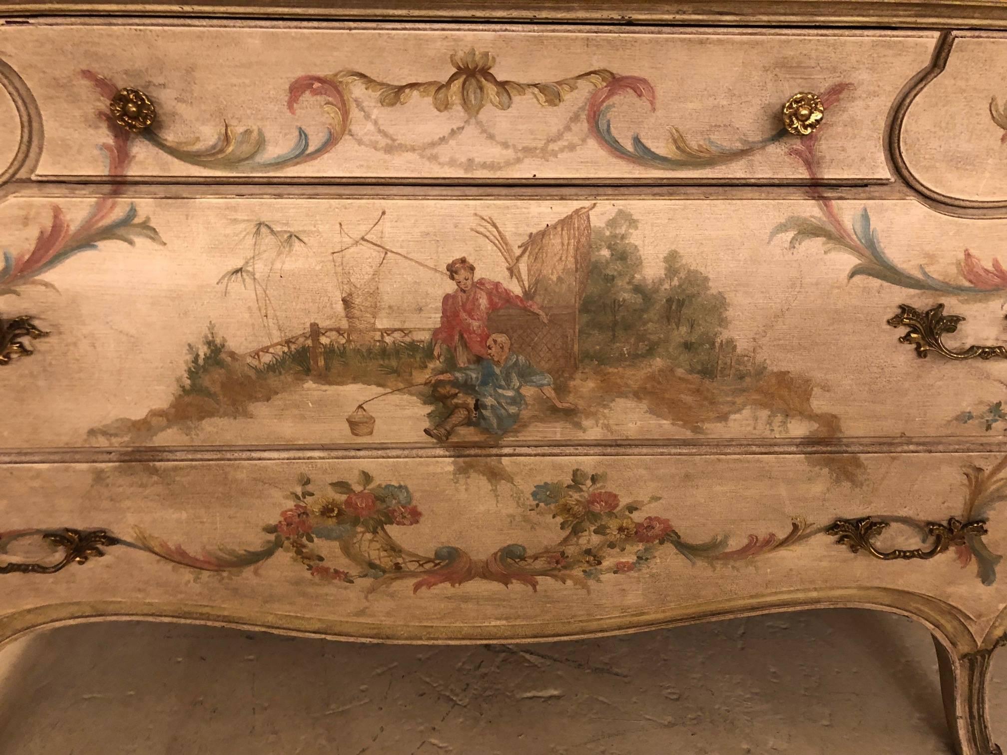An antique Venetian scenic chinoiserie bombe painted commode with a faux marble top. This finely detailed commode is done in an off white paint background with a brownish beige painted wood top to depict a marble. The center top drawer flanked by by