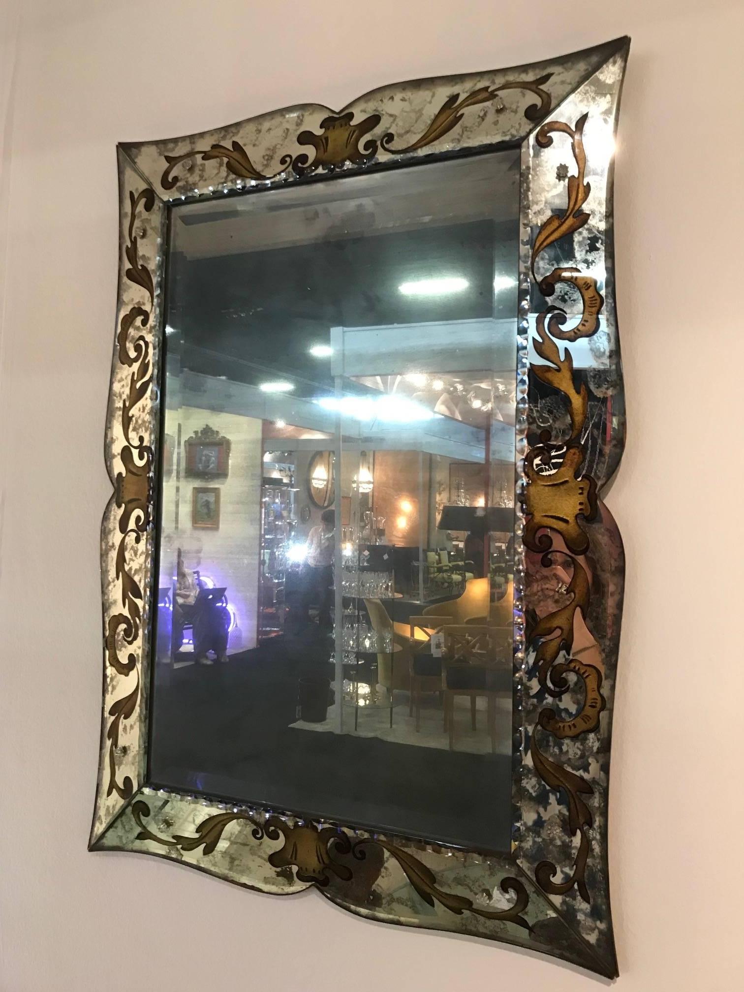 An elegant verre eglomise mirror with gilded and chiselled frame detail. Central mirror plate is antiqued.