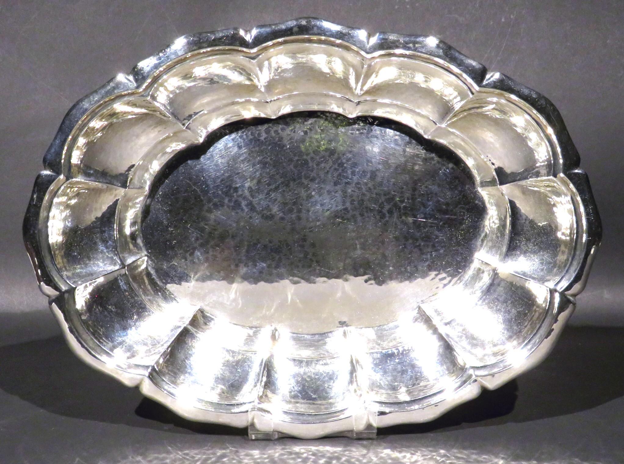 A very elegant continental silver fruit bowl or bread tray, showing an oval shaped and scalloped body with a recessed interior, exhibiting a beautifully subtle planished (hammered) surface overall. rising to a wavy roll-over rim and 
Bears impressed
