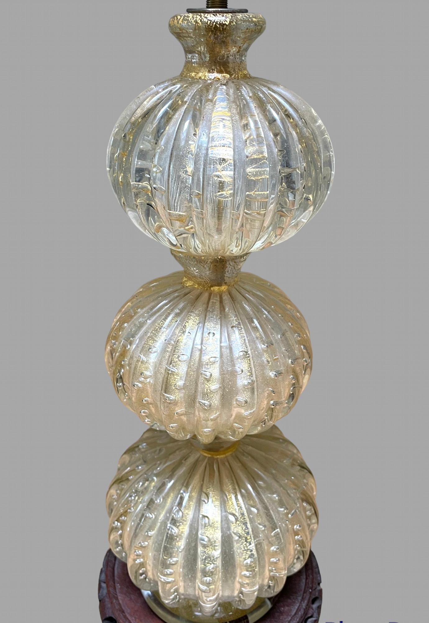 A very attractive three bubble murano lamp on a wooden base c1955. Pat Tested

Murano Glass is made on the island of Murano, located within the city of Venice in Northern Italy. This glass is made from silica, soda, lime and potassium melted