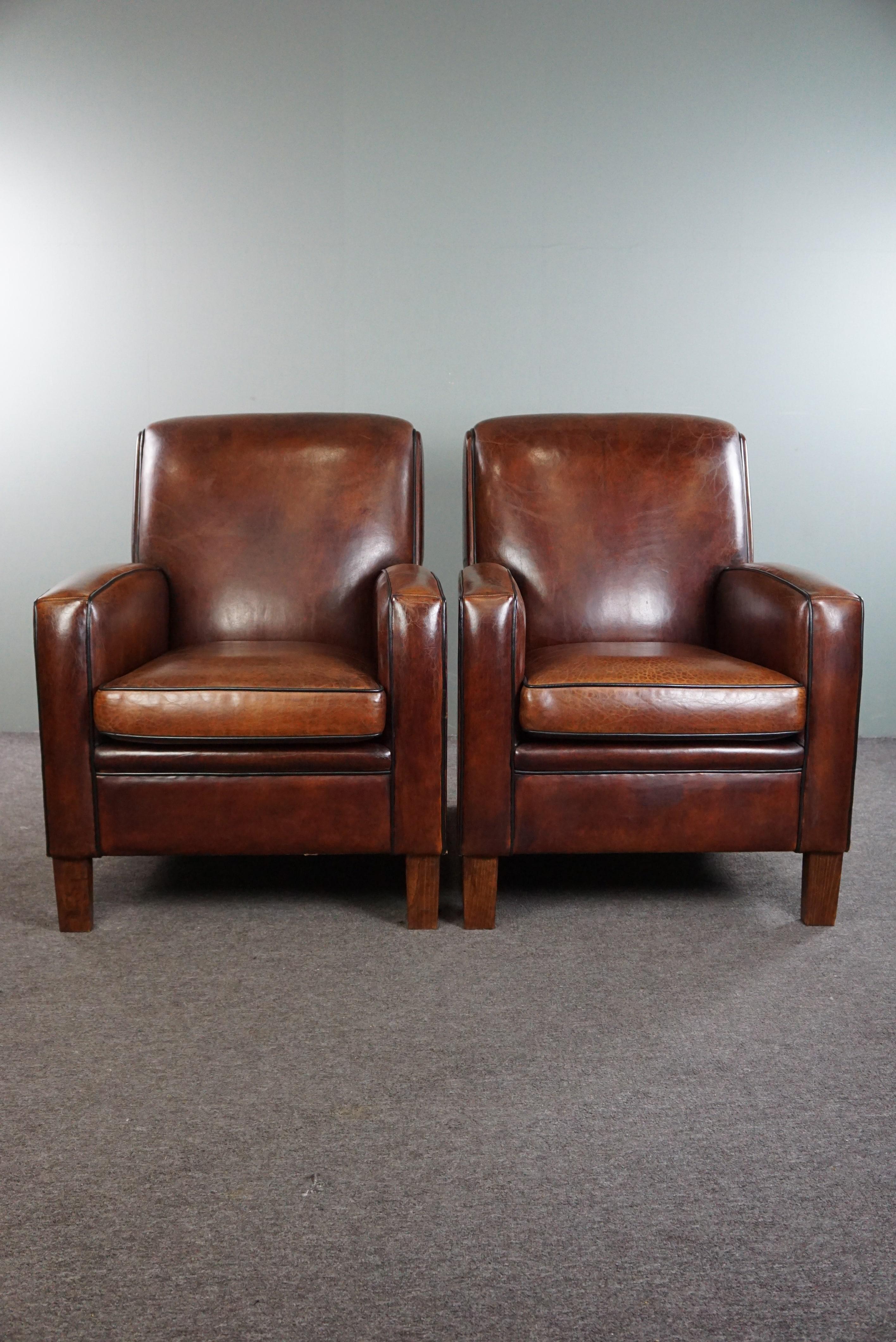 Offered: this very beautiful set of 2 top-quality Art Deco design armchairs made of first-class sheep leather.

This stunning set, crafted from only the finest materials, features a detachable seat cushion and offers exceptional seating comfort. The