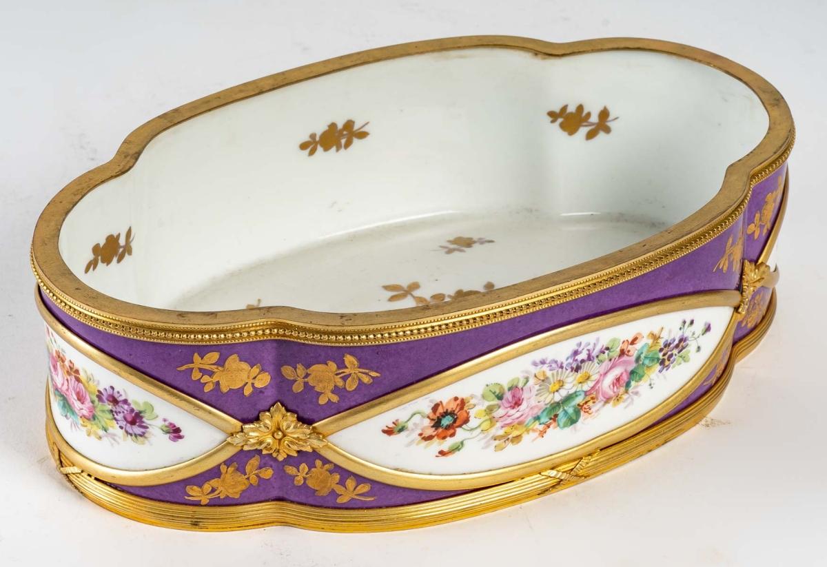 A very beautiful Sèvres porcelain jardinière, 19th century
Very nice Jardinière in Sèvres porcelain in a very rare violet colour, signed, decorated with flowers all around the piece and surrounded by high quality gilded bronze with a very detailed