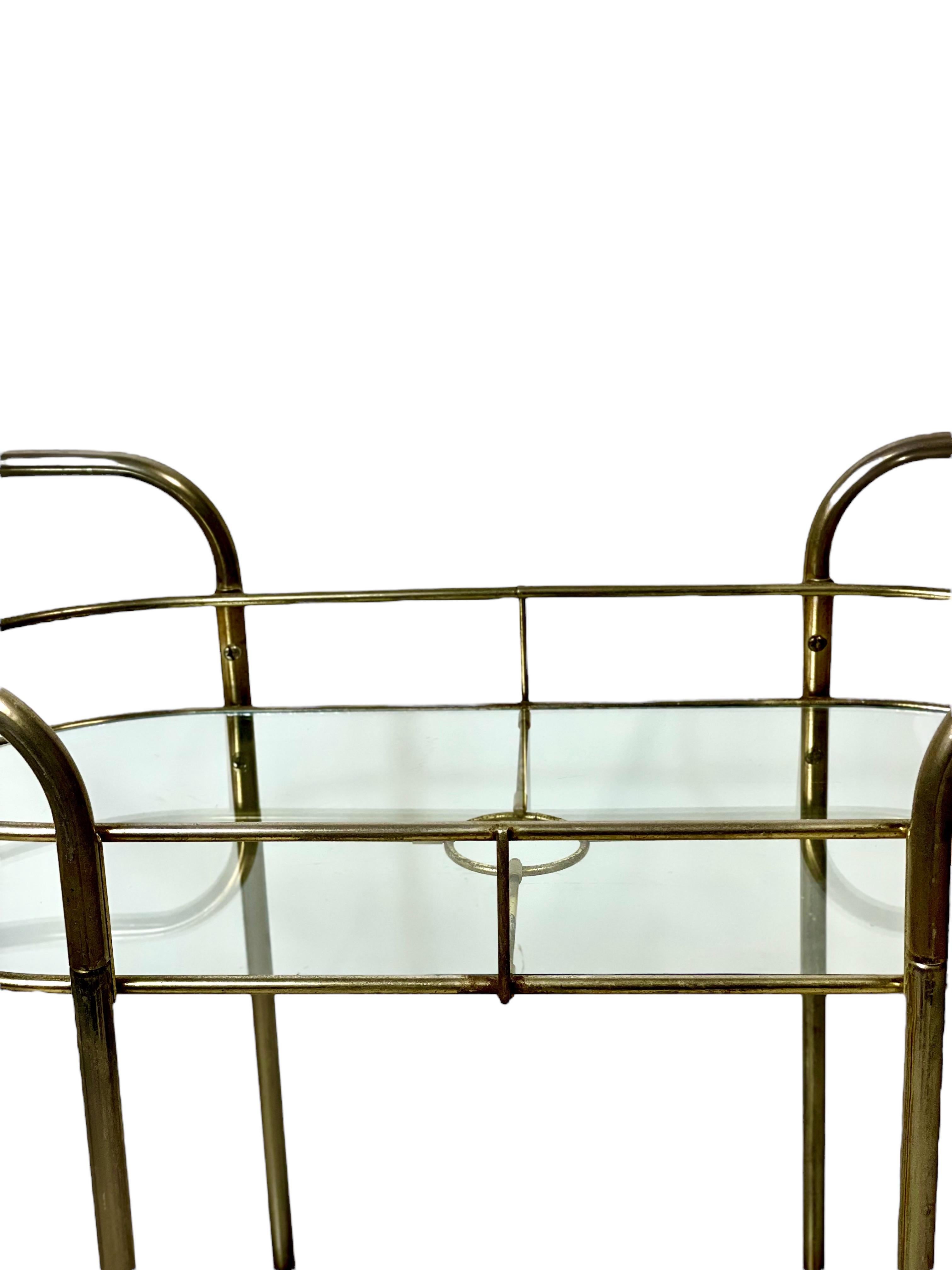 A very chic 1960s bar cart, or drinks serving trolley, featuring a light and dynamic two-tier structure made from tubular chrome. Oval-shaped inset smoked glass shelves echo the elegant shape of the frame, while swivel castors and stylish push
