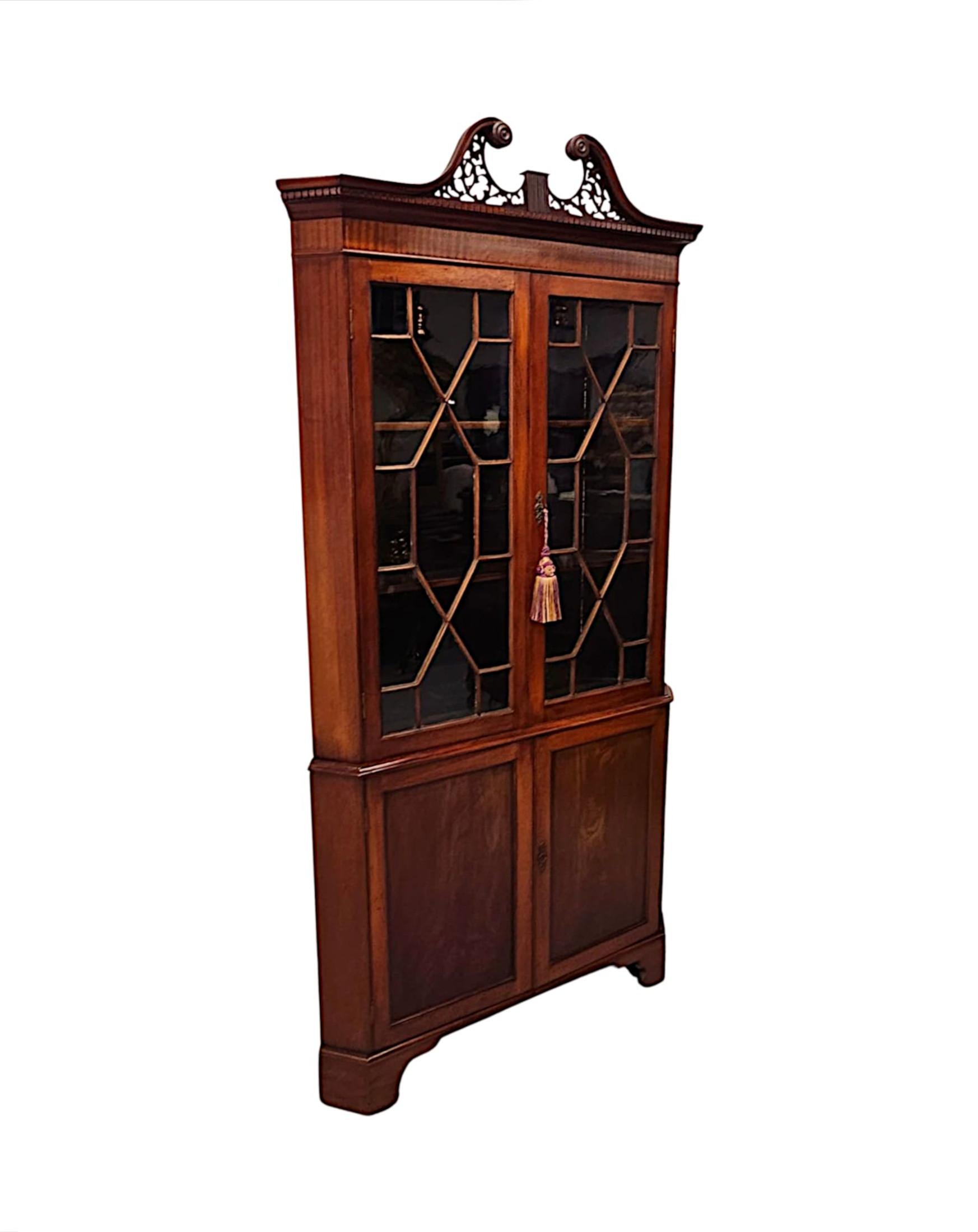 A very fine 19th Century Georgian style finely figured mahogany corner cabinet of exceptional quality, finely hand carved with gorgeously rich patination and grain.  The broken swan neck pediment with stunningly carved open fretwork, foliate and