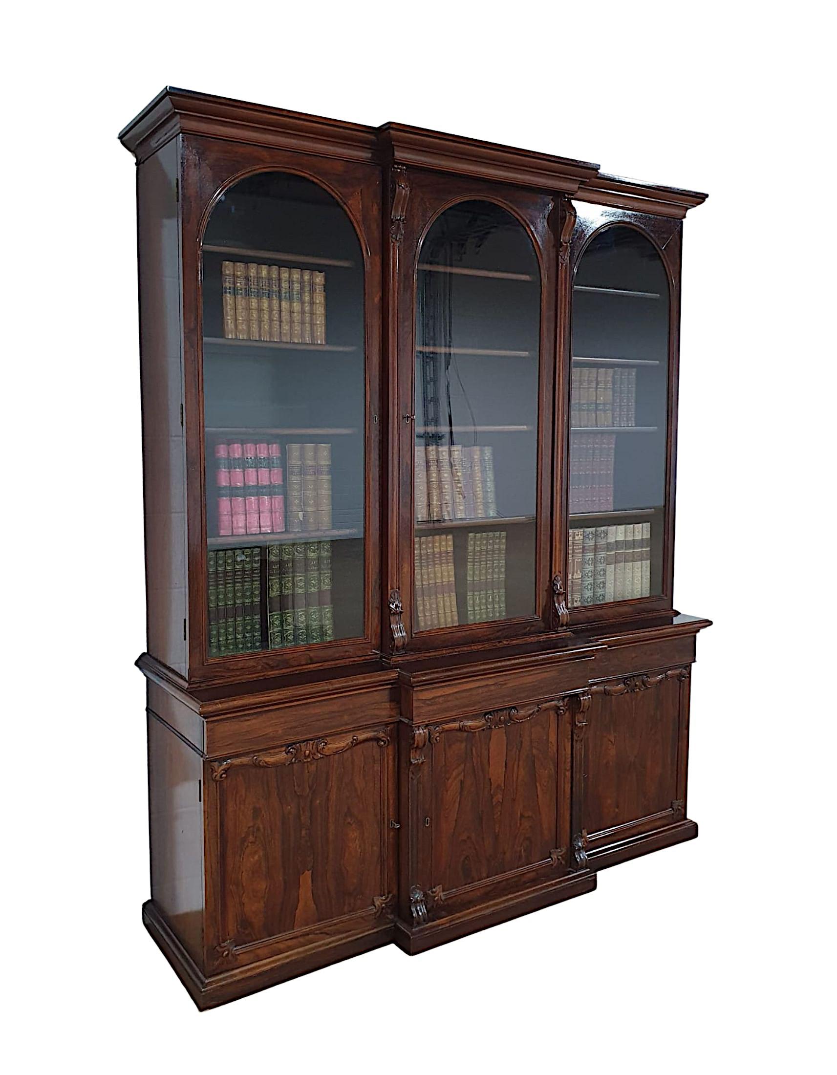 A very fine 19th century fruitwood three door breakfront bookcase, beautifully hand carved with a rich patina. The moulded stepped cavetto pediment raised over three cockbeaded arch top single glazed glass panelled doors with gorgeous corbel detail