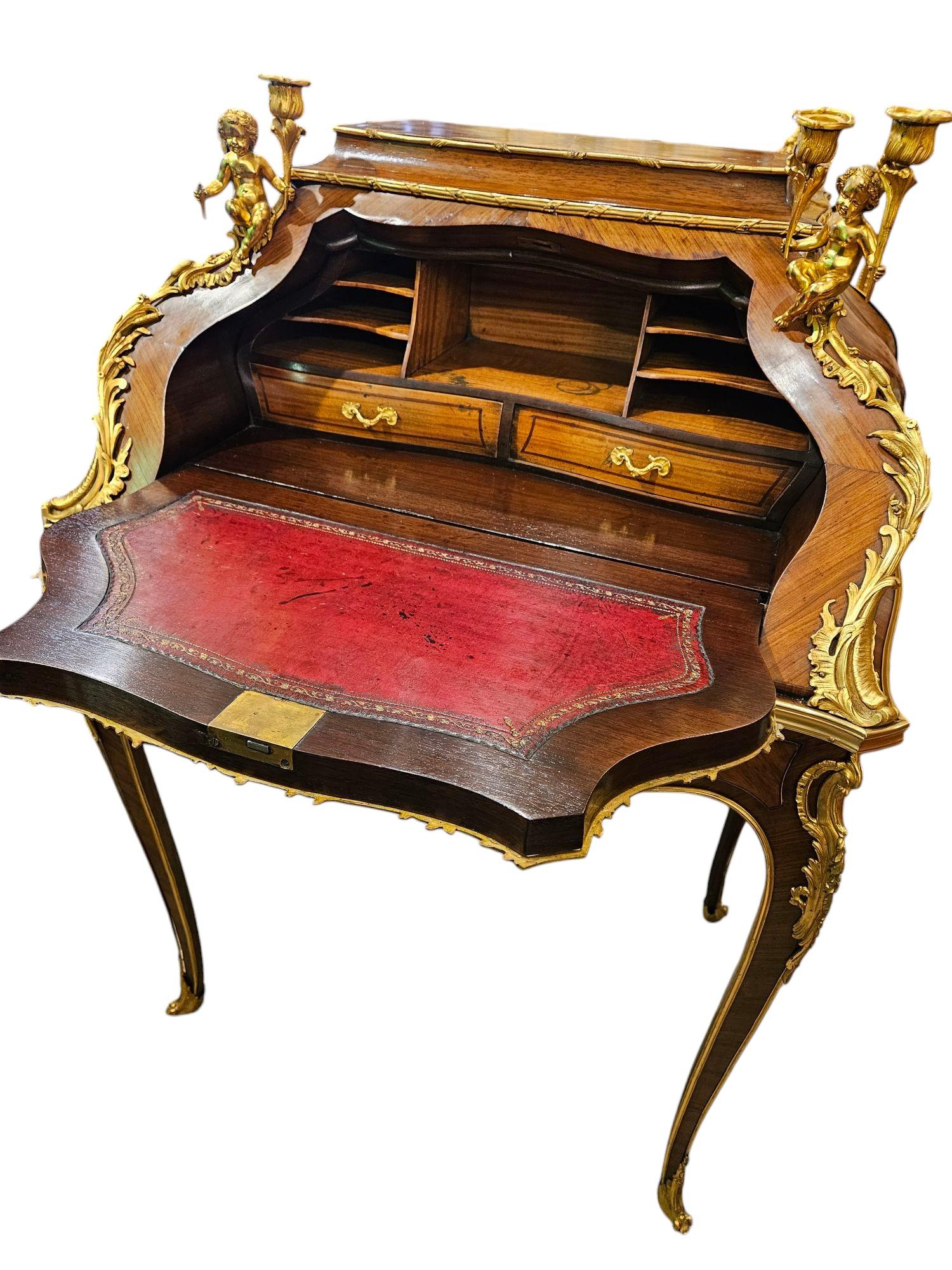 Bureau de dame en bois de roi, tulipier et parqueterie, monté en bronze doré, datant des années 1880.
La monture est de la Maison Maison Mottheau. 
Jolie forme de bombe 
Décorations en marqueterie de soleil et chandeliers d'anges
Facture également