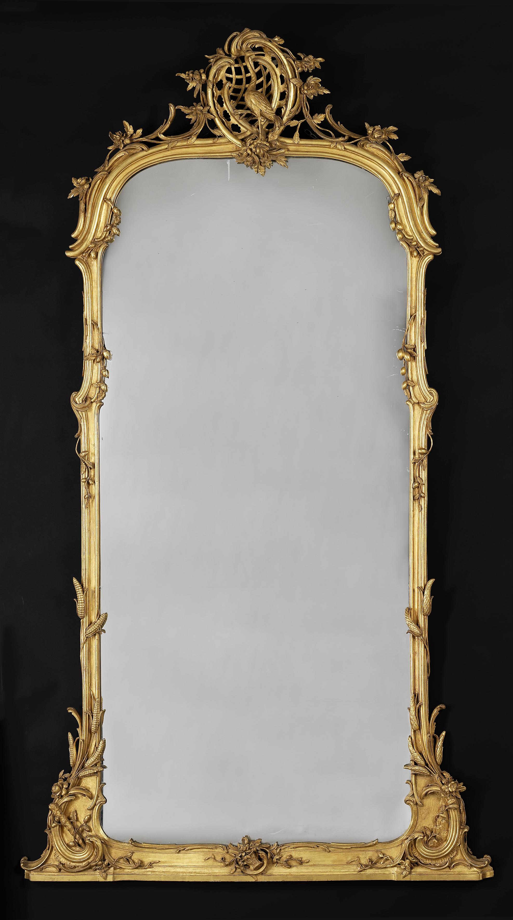 A very fine carved giltwood mirror.

German, circa 1860.

The shaped moulded frame carved with wheat sheafs and entwined foliate forms, surmounted by an openwork rocaille cartouche centred by the figure of a Crane.