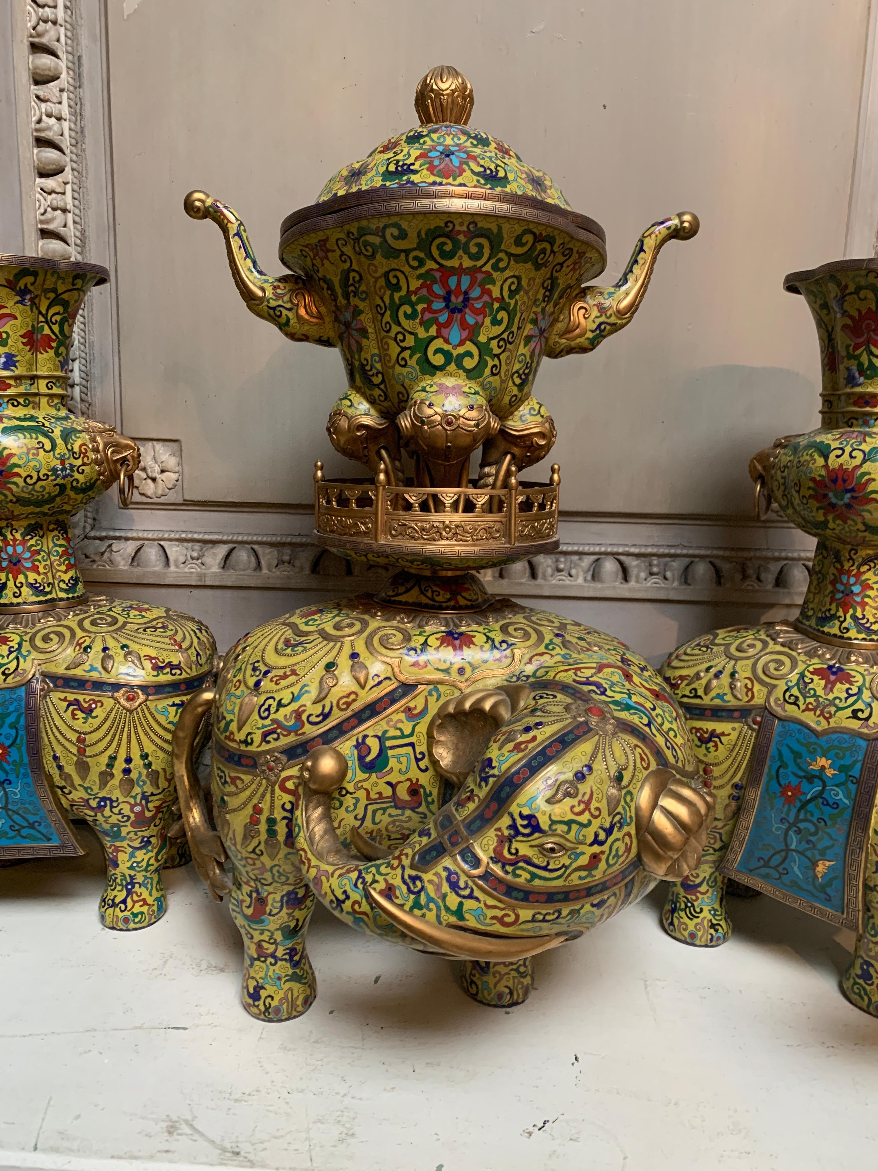 A very fine mid-20th century Chinese yellow and blue cloisonne five piece alter set depicting elephants. The eleven piece set includes 5 elephants, two gu-shaped vases,  two candlesticks and a ding-shaped censer with a domed lid. 