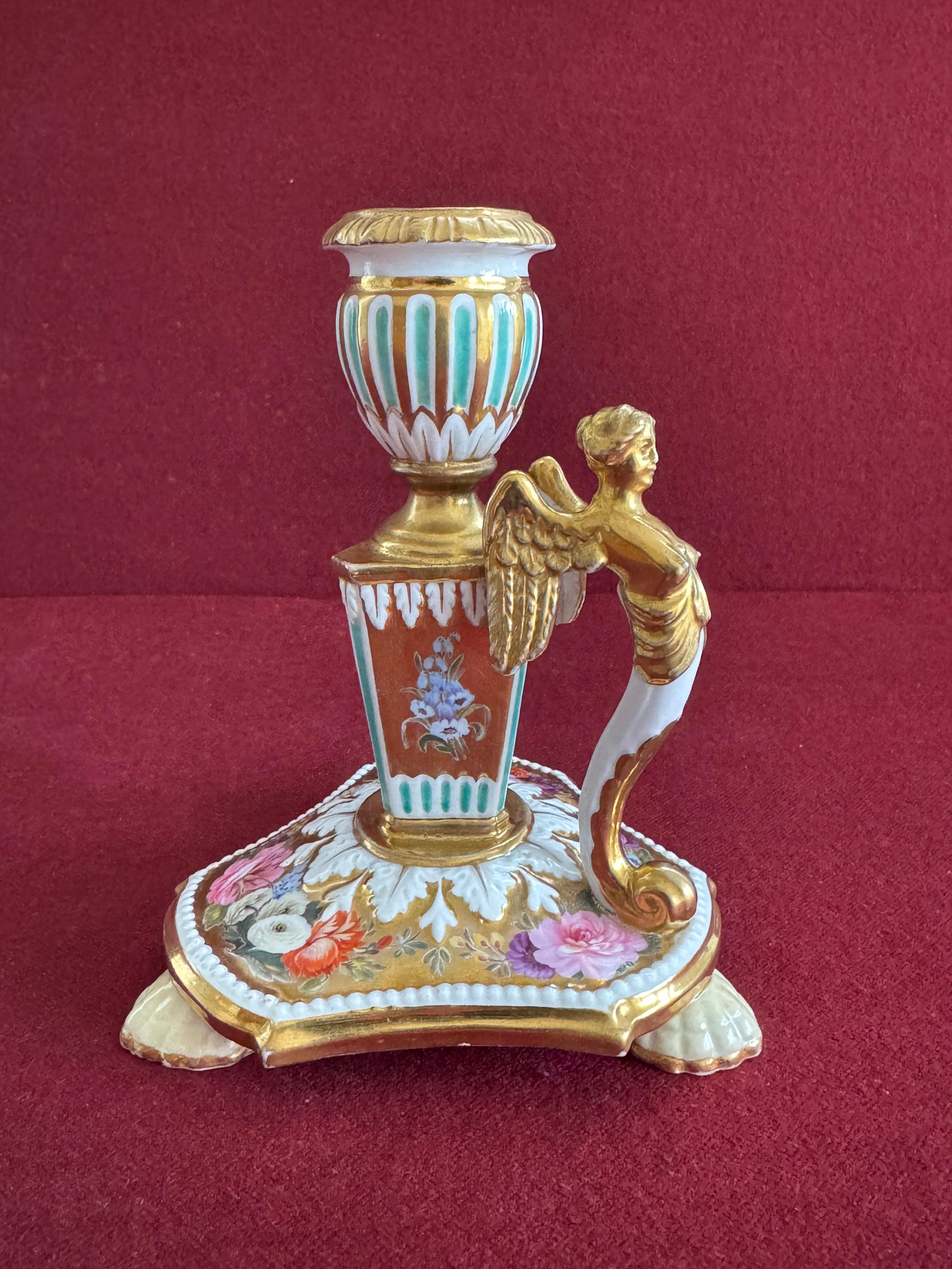 A rare and unusual Coalport porcelain library candlestick c.1815-20. Of French Empire style standing on three shell feet, the urn shaped sconce on a triangular column, the image handle modelled as a winged female figure. The solid gold ground