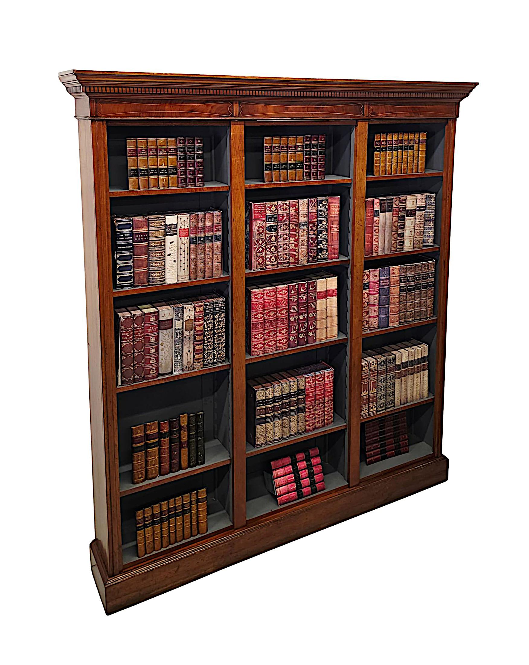 A very fine Edwardian well figured mahogany three section open bookcase of narrow proportions, beautifully carved with rich patination, fine grain and delicate line inlay.  The stepped and fluted cavetto pediment with gorgeous dentil moulded detail