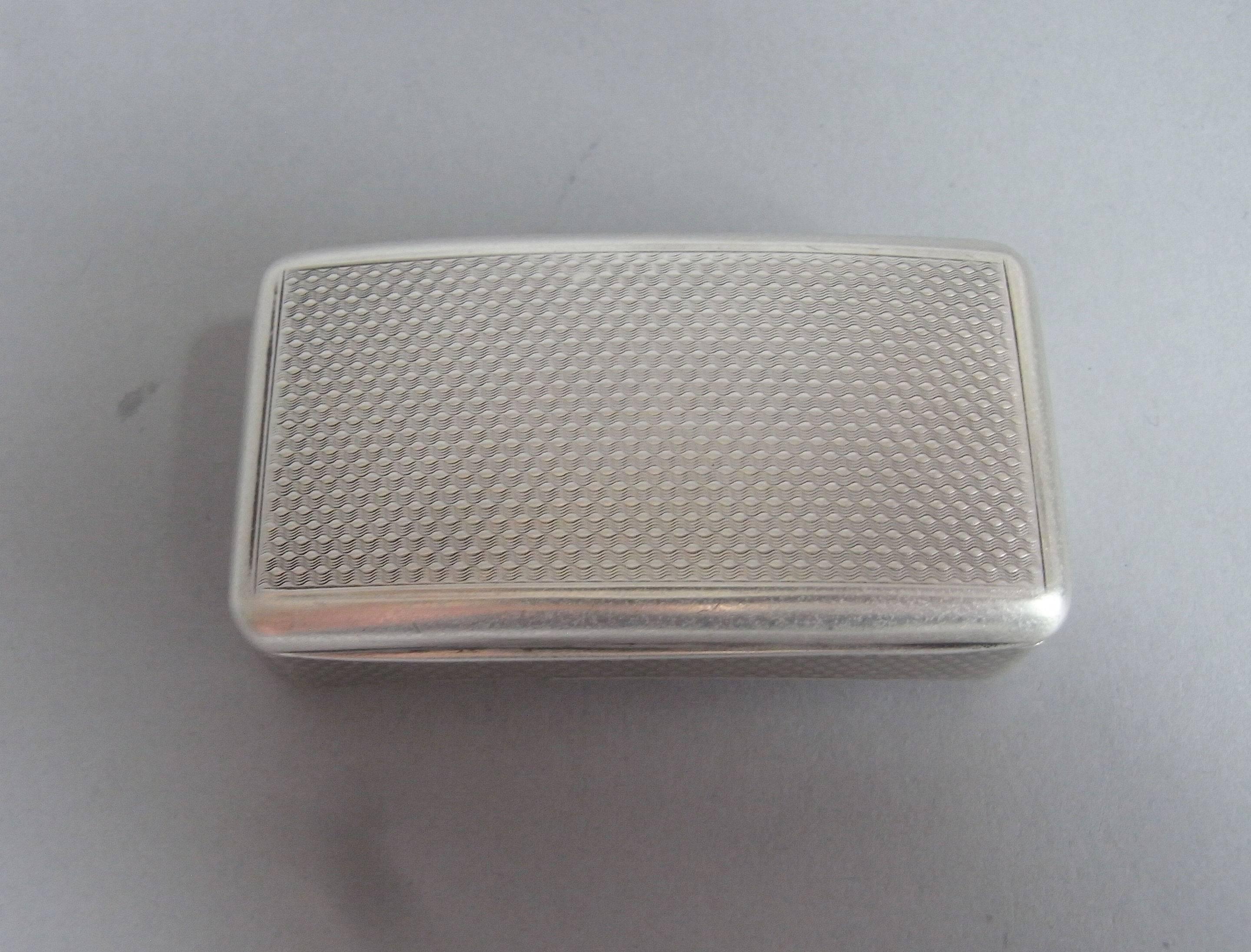 The snuff box is of broad rectangular form with a slightly curved base and cover. Both, the cover, base and sides are decorated with crisp engine turned designs. The interior displays exceptional gilding and is very well marked. The quality of