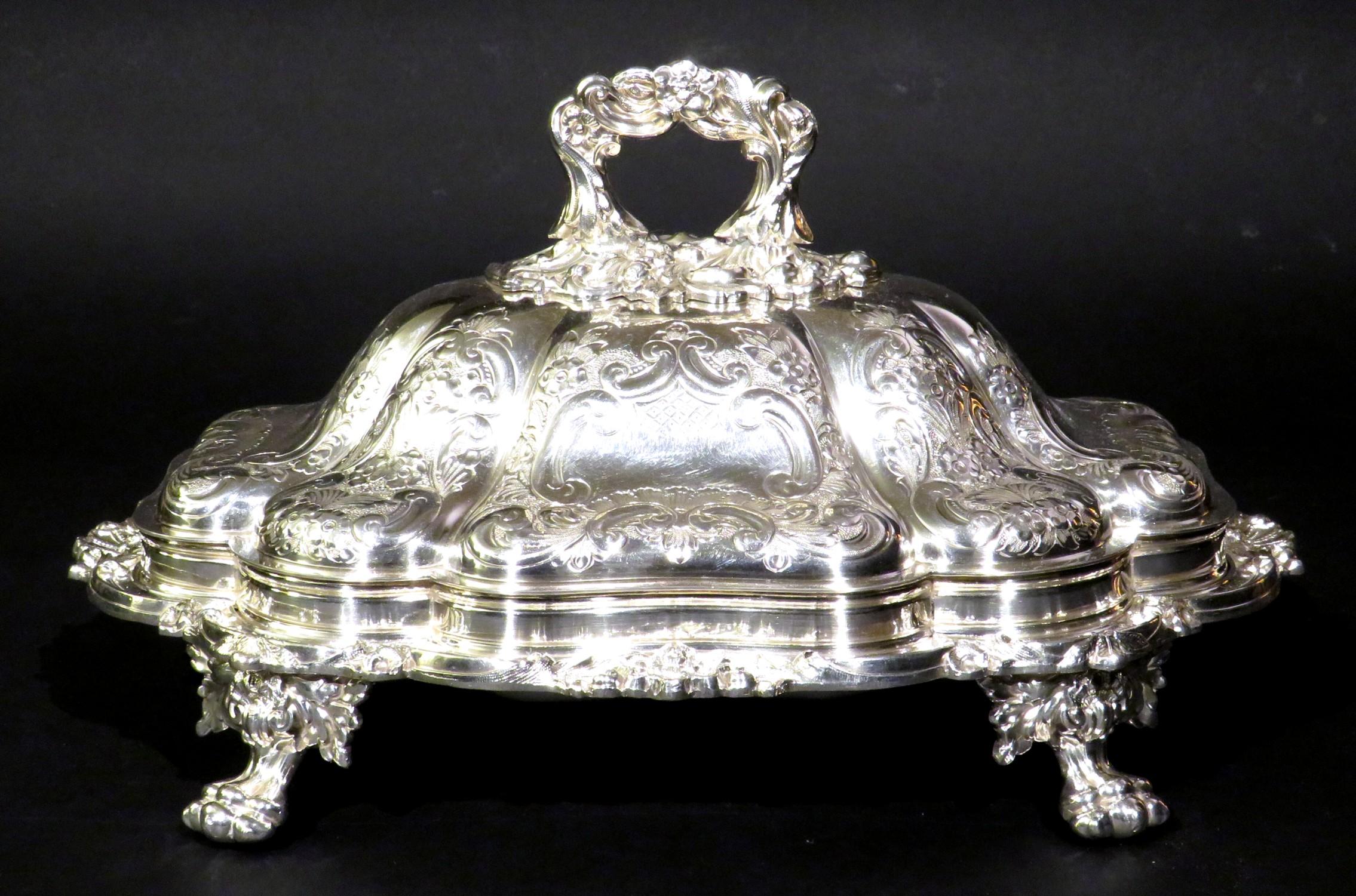 Un piatto da portata in argento placcato Giorgio V molto fine e pesante, con una base di forma curvilinea dotata di un coperchio a cupola con manico staccabile, riccamente decorato nel complesso con dettagli incisi in rilievo e fogliacei insieme a