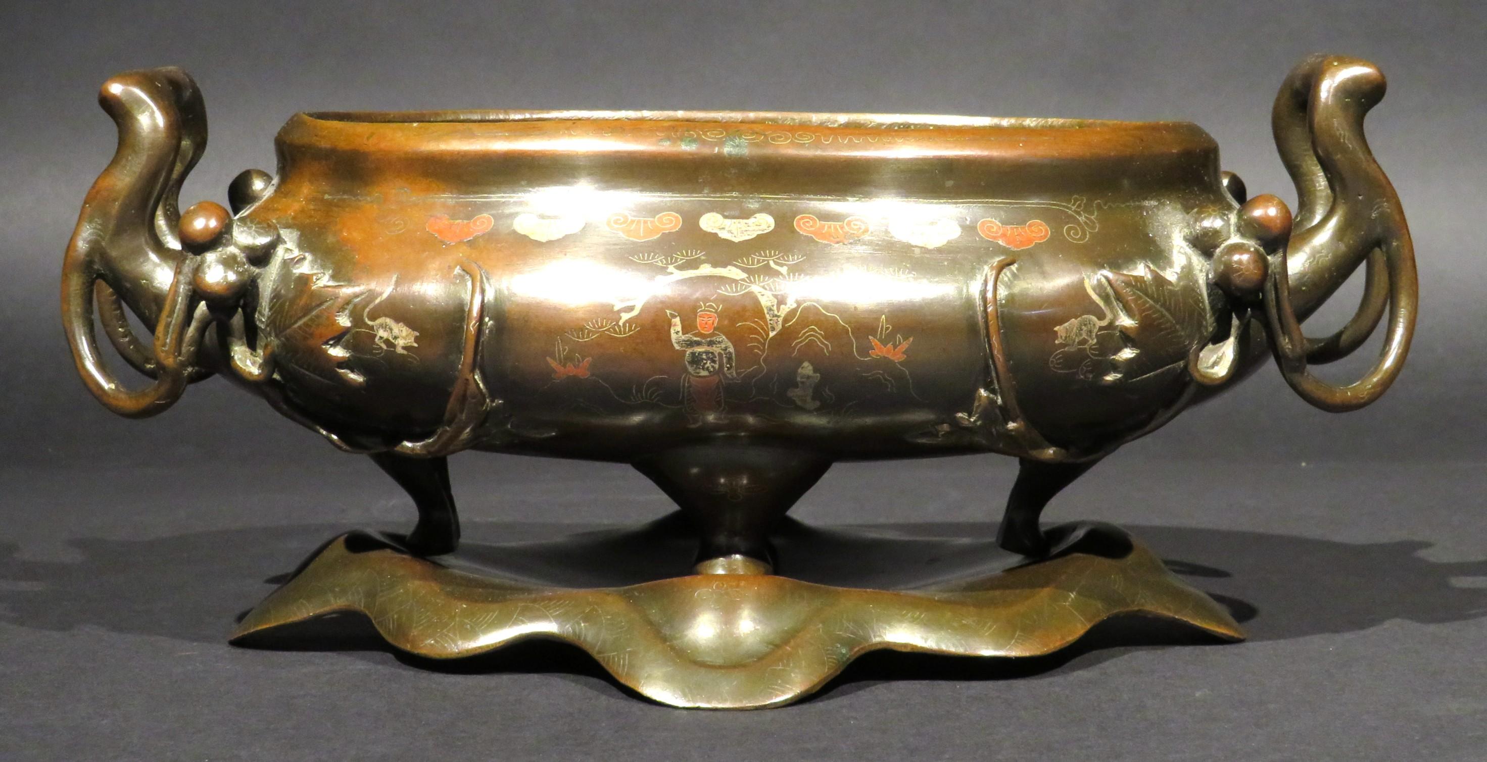 A very fine Japanese bronze Suiban (planter) of bellied oval form, richly decorated overall with hand enamelled and 'shibuichi' & 'shakudo' motifs, depicting geometric designs, pine trees, exotic beasts, priestly & scholarly figures, mounted at both