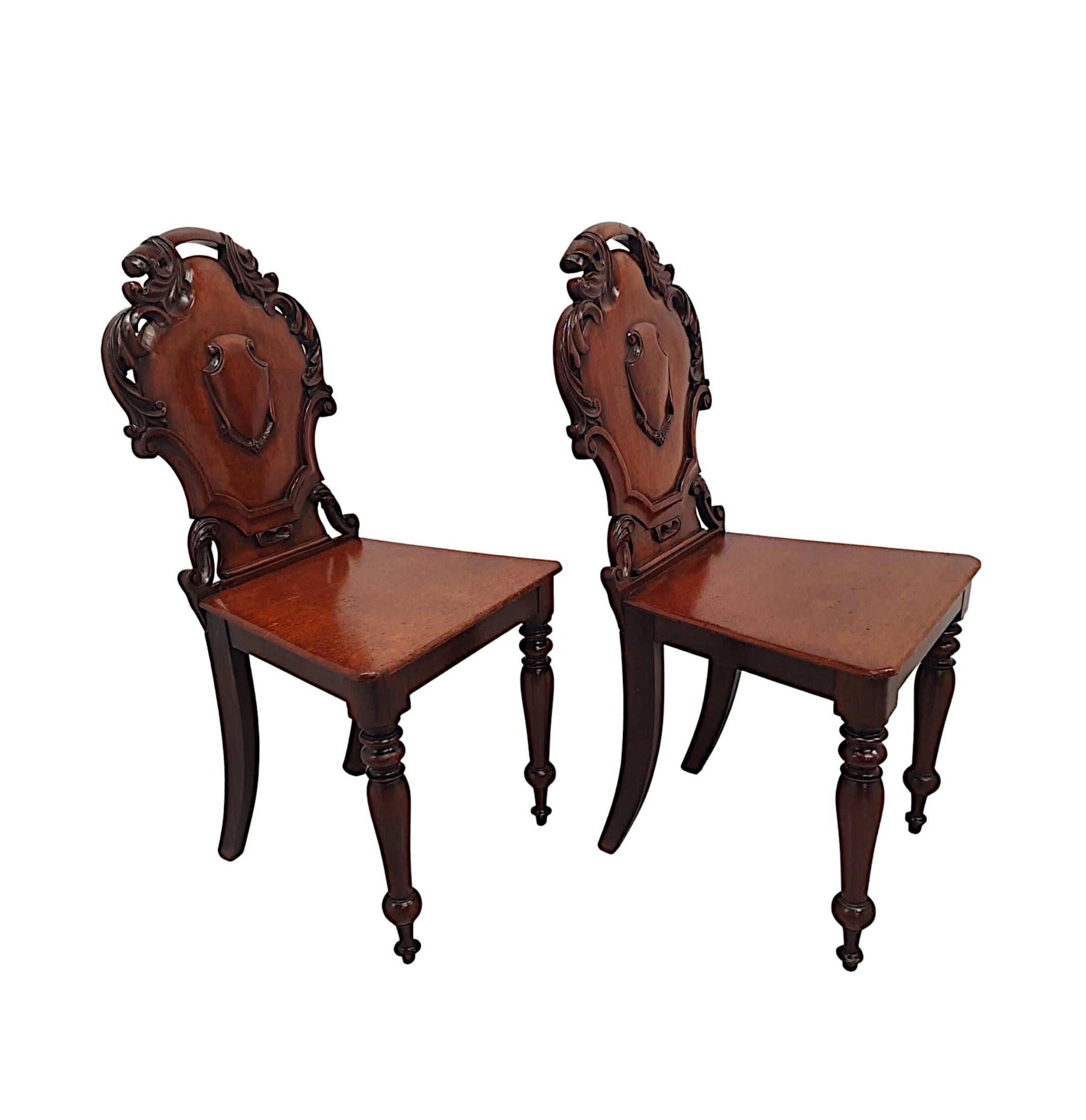 A very fine pair of 19th Century well figured, mahogany hall chairs, fabulous hand carved with gorgeously rich patination and grain.  The shaped and pierced shield back with exquisite motif detail comprising of a beautifully shaped shield with