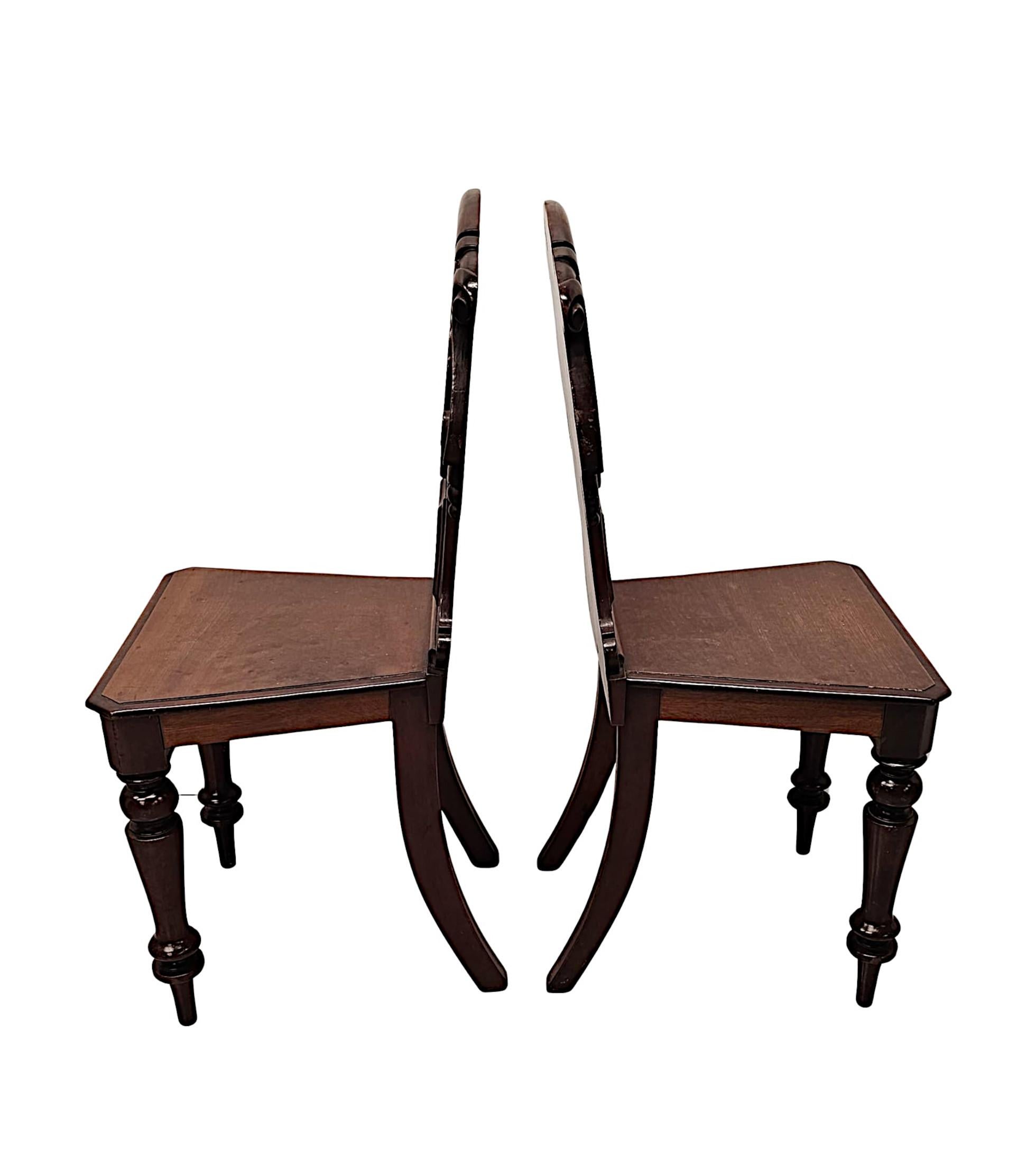 Une très belle paire de chaises de hall en acajou bien figuré du 19ème siècle, fabuleusement sculptées à la main avec une patine et un grain magnifiquement riches.  Le dos en forme de bouclier, mouluré et cannelé, présente de magnifiques détails