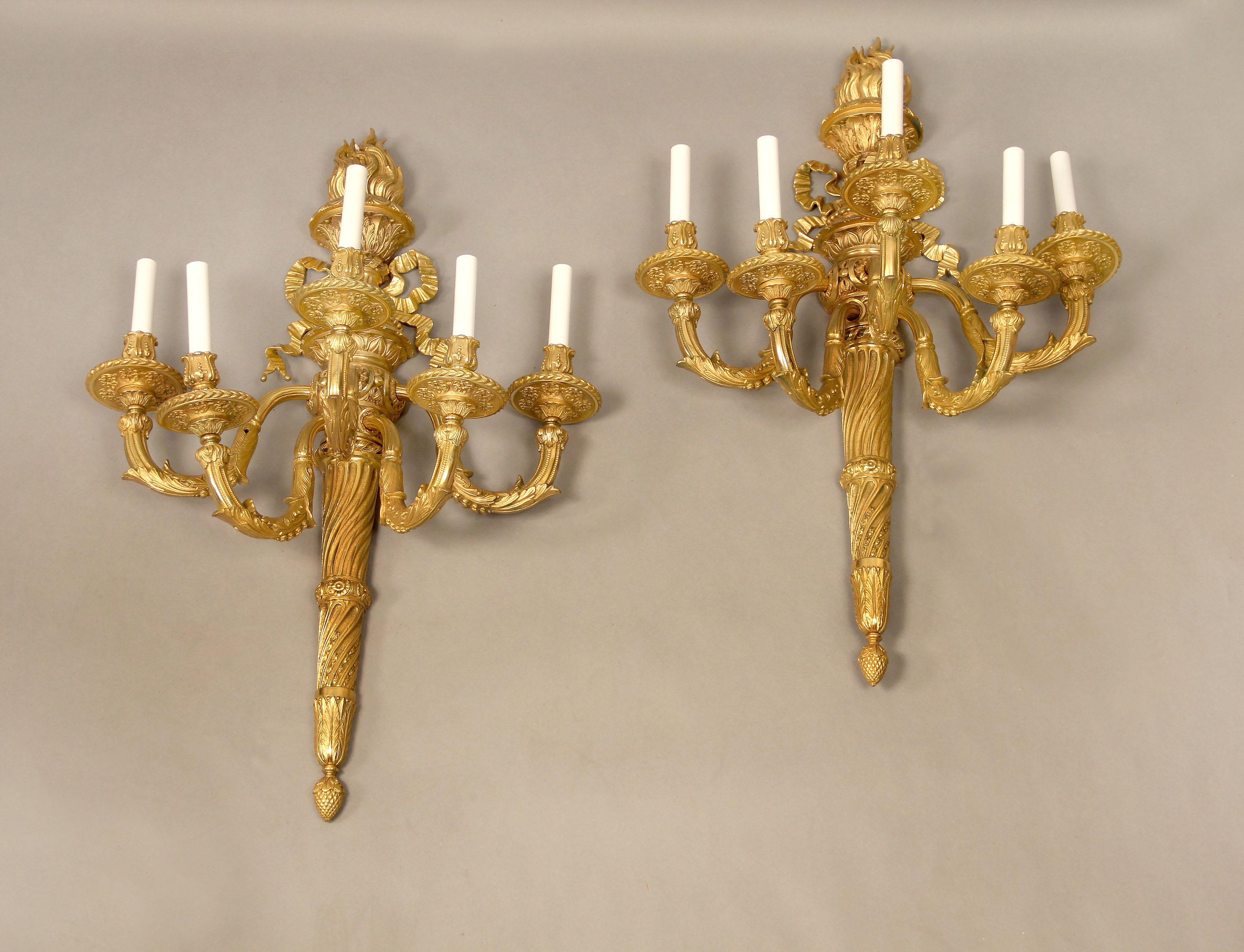 A Very Fine Pair of Early 20th Century Gilt Bronze Five Light Sconces

Each sconce shaped as a spiral torch decorated with bow knotted ribbon and a flame emanating at the top.

 