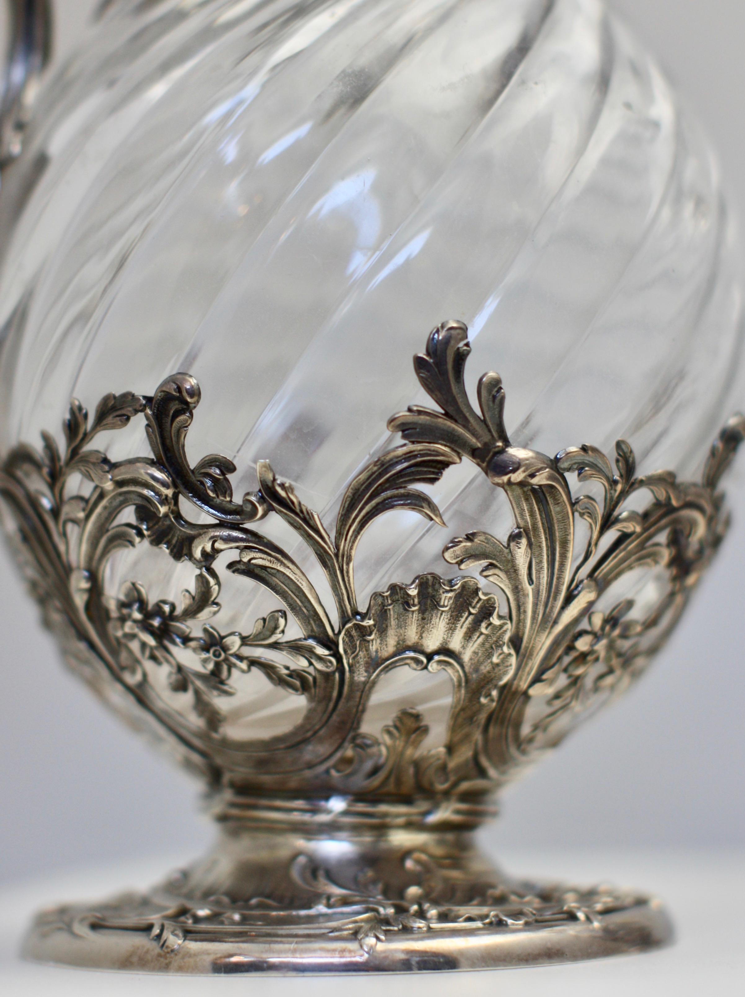 Pareja muy fina de jarras francesas de clarete de vidrio montadas en plata, París, hacia 1880, Marca de VB. Los cuerpos bulbosos de vidrio estriado en espiral, cada uno con pie y cuello circulares de plata, asa con tapa de hoja y tapa abatible con
