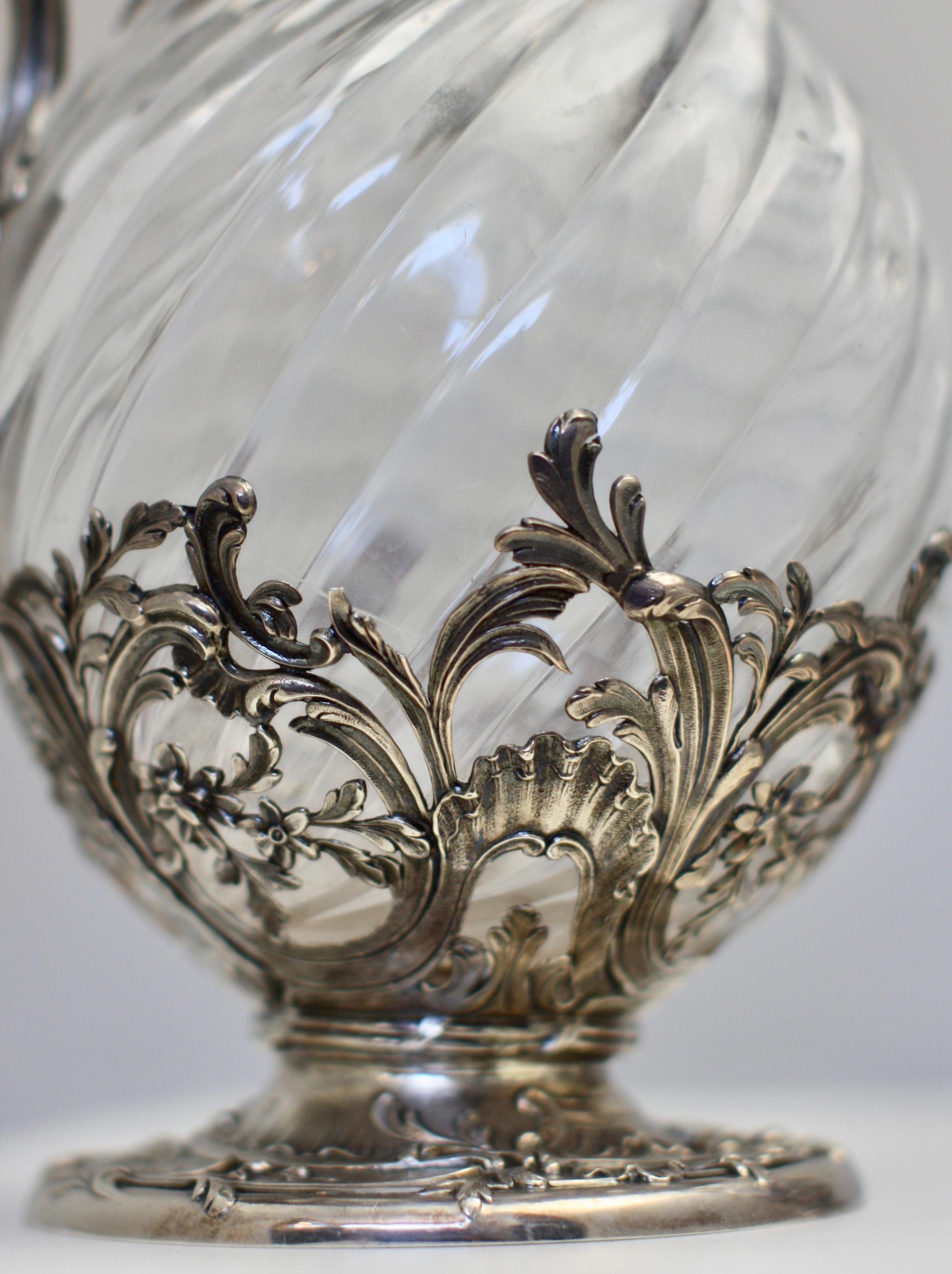 A very fine pair of French silver-mounted glass claret jugs, Paris, circa 1880, Mark of VB. The bulbous spiral-fluted glass bodies each with silver circular foot and neck, leaf-capped handle and hinged cover with foliate thumb piece.
Measures: