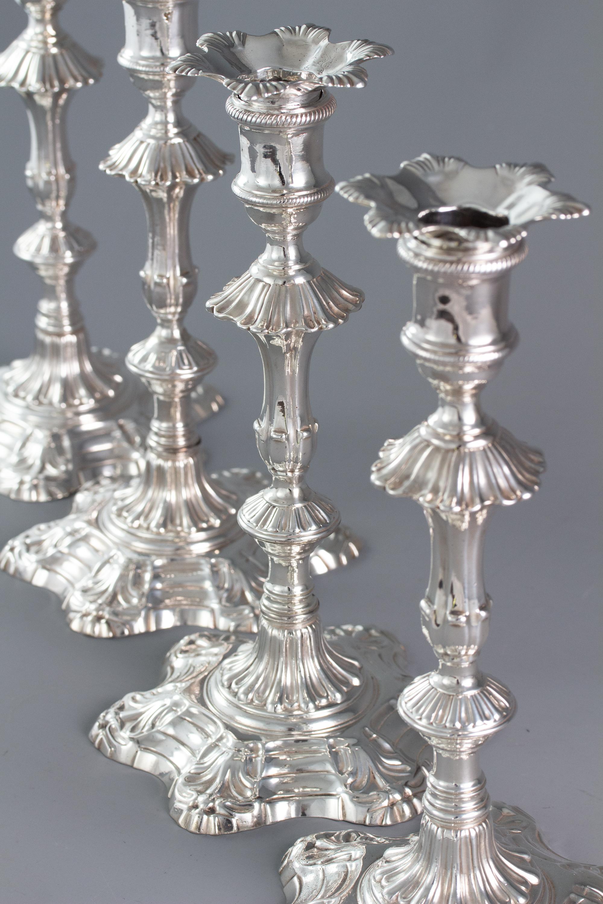 An extremely fine set of cast silver George II table candlesticks of hexagonal form with shell corners. The fluted pedestal column rising to a further fluted knop below a cotton reel capital with rope twist decoration. Conforming sconces. Each stick