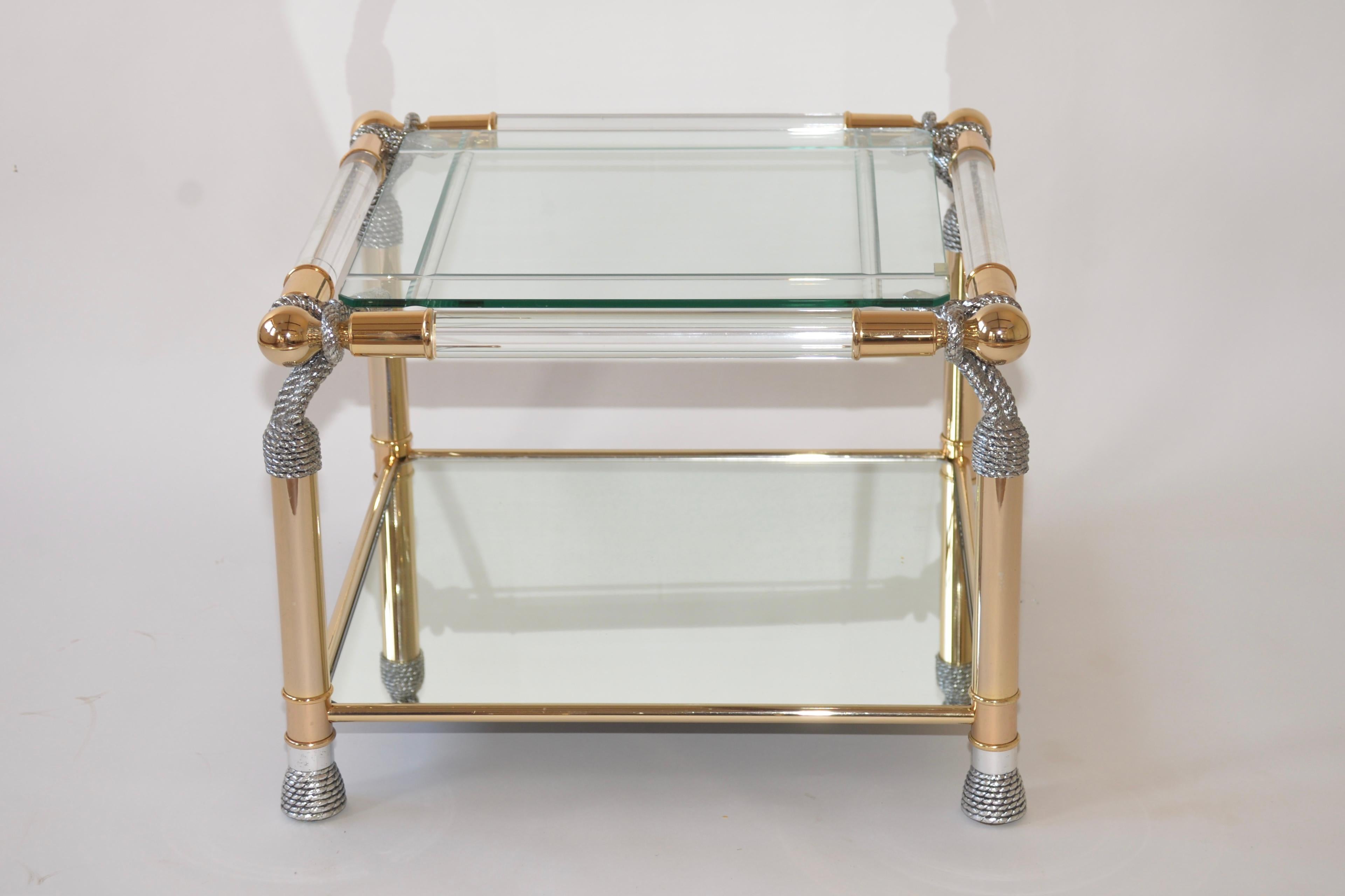 Fabulous Lucite, polished brass and glass Hollywood Regency style coffee table. The top shelf is beveled glass and the shelf below is mirrored glass. Each corner has a twisted rope effect to make this a very striking item.