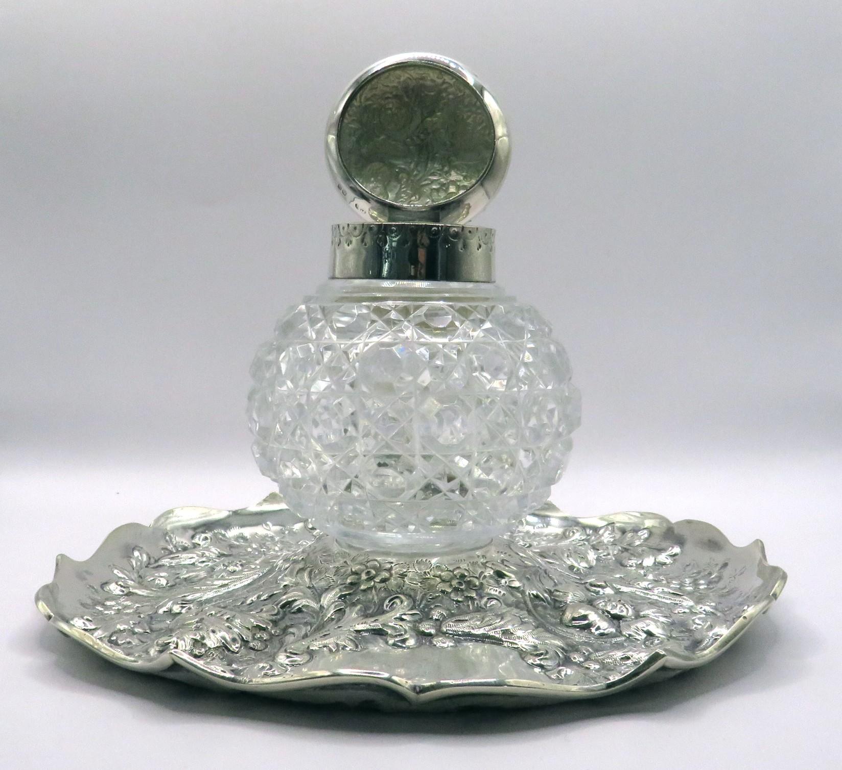 The robust globular shaped & cut glass body is fitted with a sterling silver collar & hinged lid, the interior retains its original removable glass reservoir. 
The inkwell sits within its impressively large & heavy sterling silver base, richly