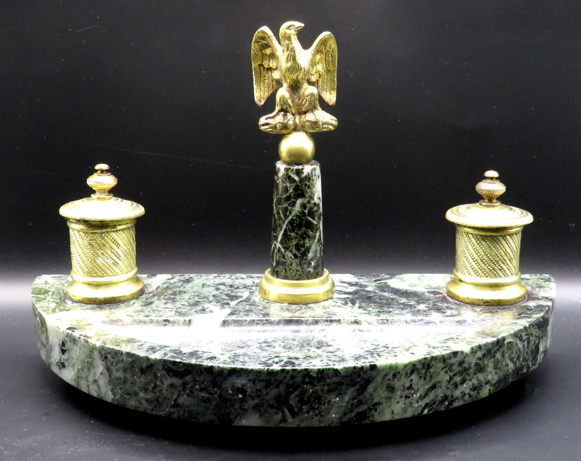 The crescent shaped & dished ‘verdi alpi’ marble base affixed with a pair of lidded gilt bronze inkpots (glass inkwells absent), decorated with fine engine turned detail, flanking a marble column surmounted by an impressive gilt bronze eagle final