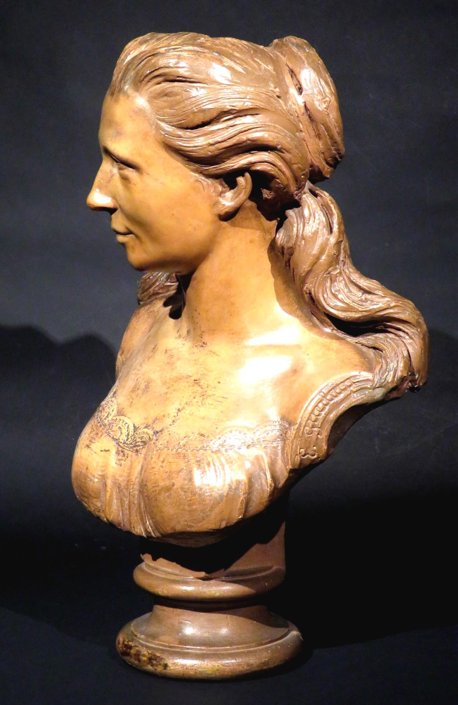 A large & finely modelled terracotta-patinated plaster portrait bust of a woman in the 18th manner, shown attired in a lace-edged bodice with her hair cascading in long tresses across both shoulders. 
Demonstrating excellent proportions & fine