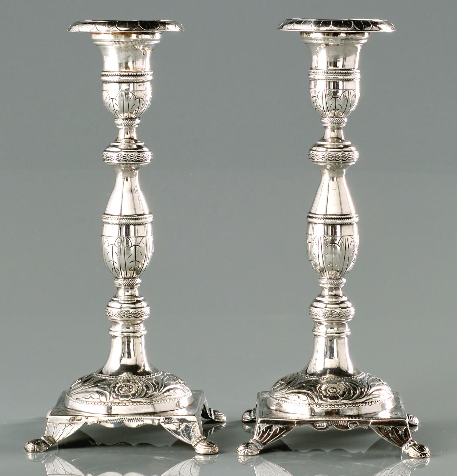 A very good & heavy pair of mid 19th century Portuguese silver (.833 fine) cast Shabbat candlesticks. 
Both showing baluster shaped stems rising from convex mounds decorated with embossed foliate motifs, to urn shaped nozzles with flaring drip