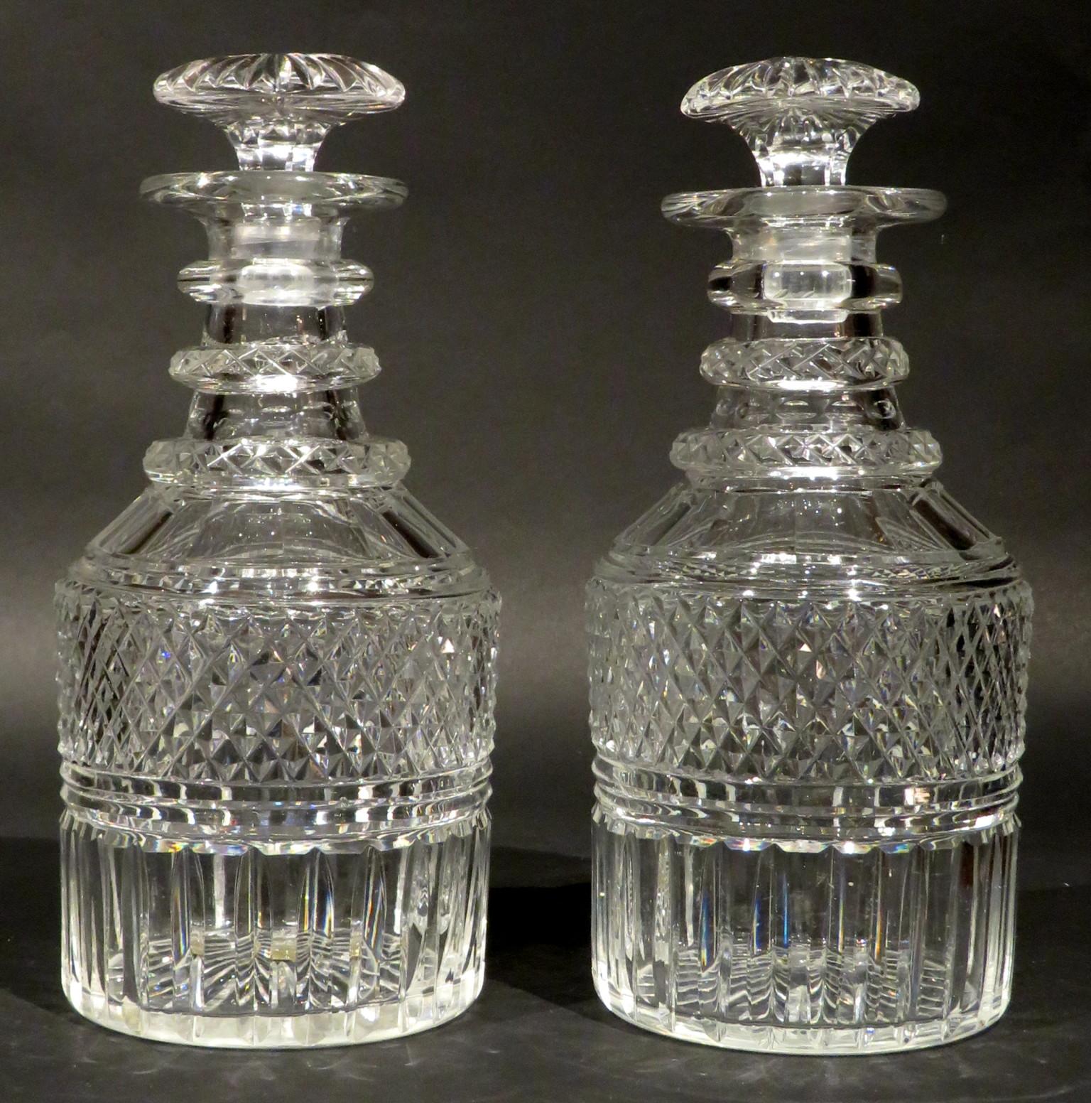 Both barrel shaped bodies showing triple ringed necks - two with facet cut detail, above shoulders decorated with broad cut flutes, over a wide band of cross-cut diamond & mitre cut vertical flutes, their undersides showing starburst cut motifs, one