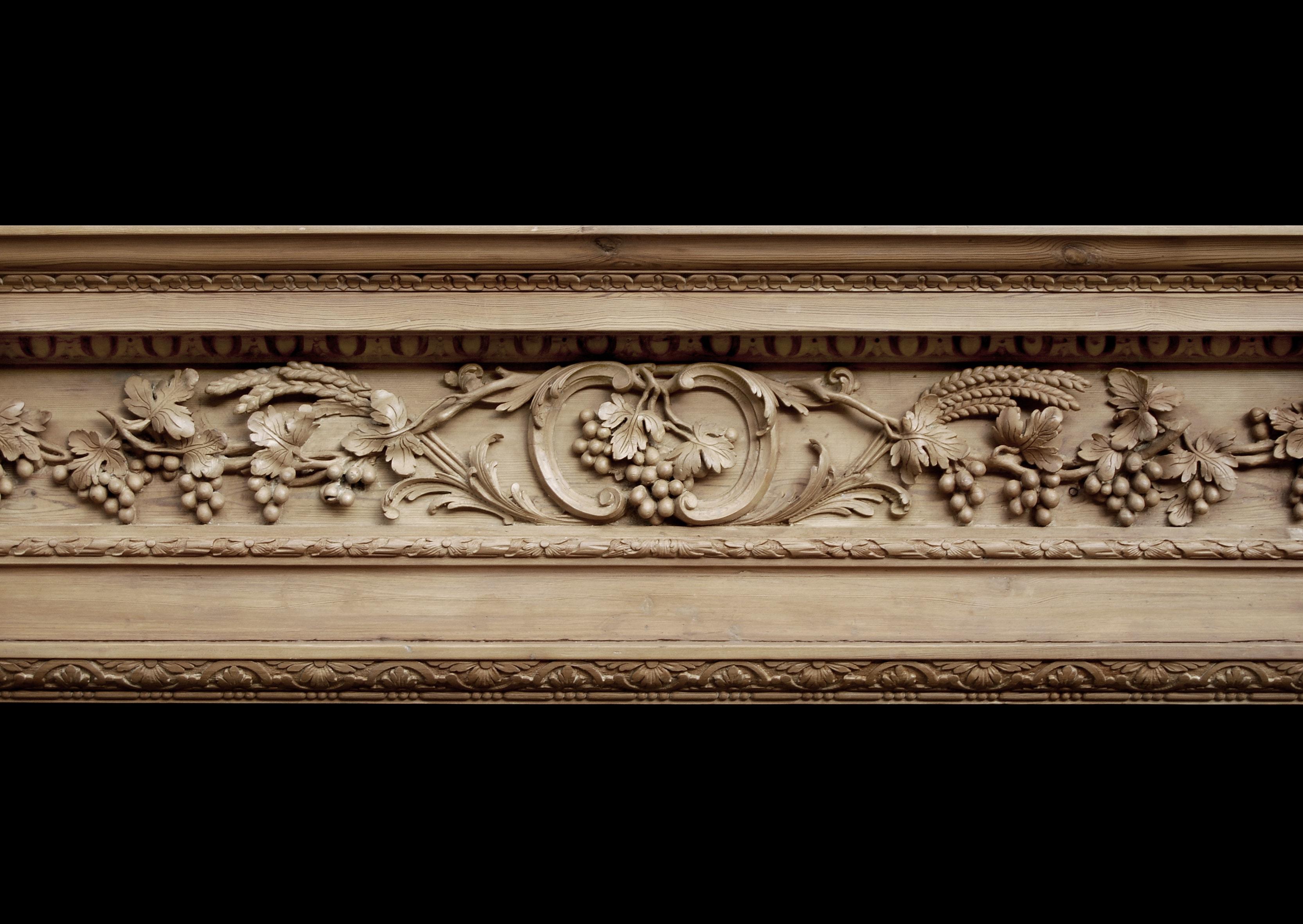 A very good quality 18th century English George II pine fireplace. The frieze finely carved with grapes, foliage and wheat sheafs surmounted by breakfront shelf with leaf moudling. The tapering panelled jambs with carved drops of foliage and grapes.