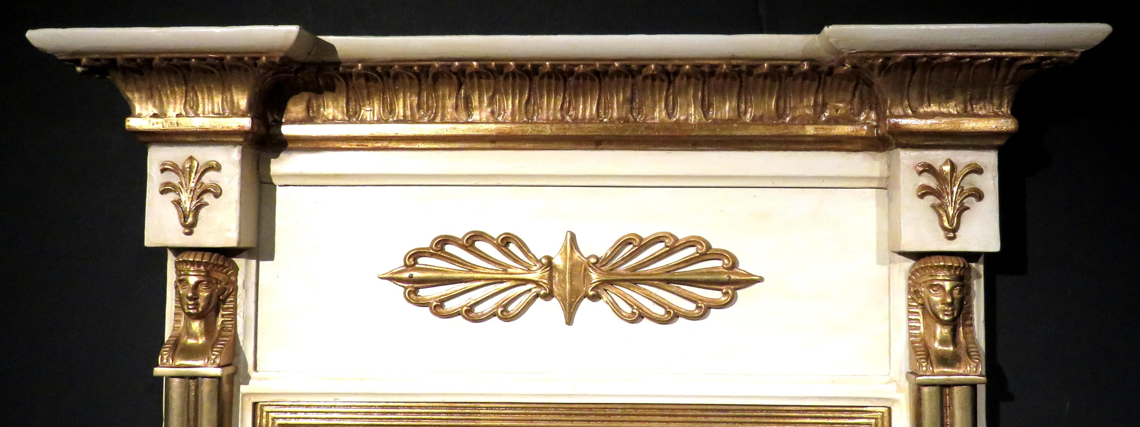 Très beau miroir console du début du 19ème siècle de la période Regency, peint en crème et doré. Le cadre présente une corniche architecturale dorée en surplomb surmontant un motif d'anthemion doré appliqué, flanqué de chaque côté de chapiteaux