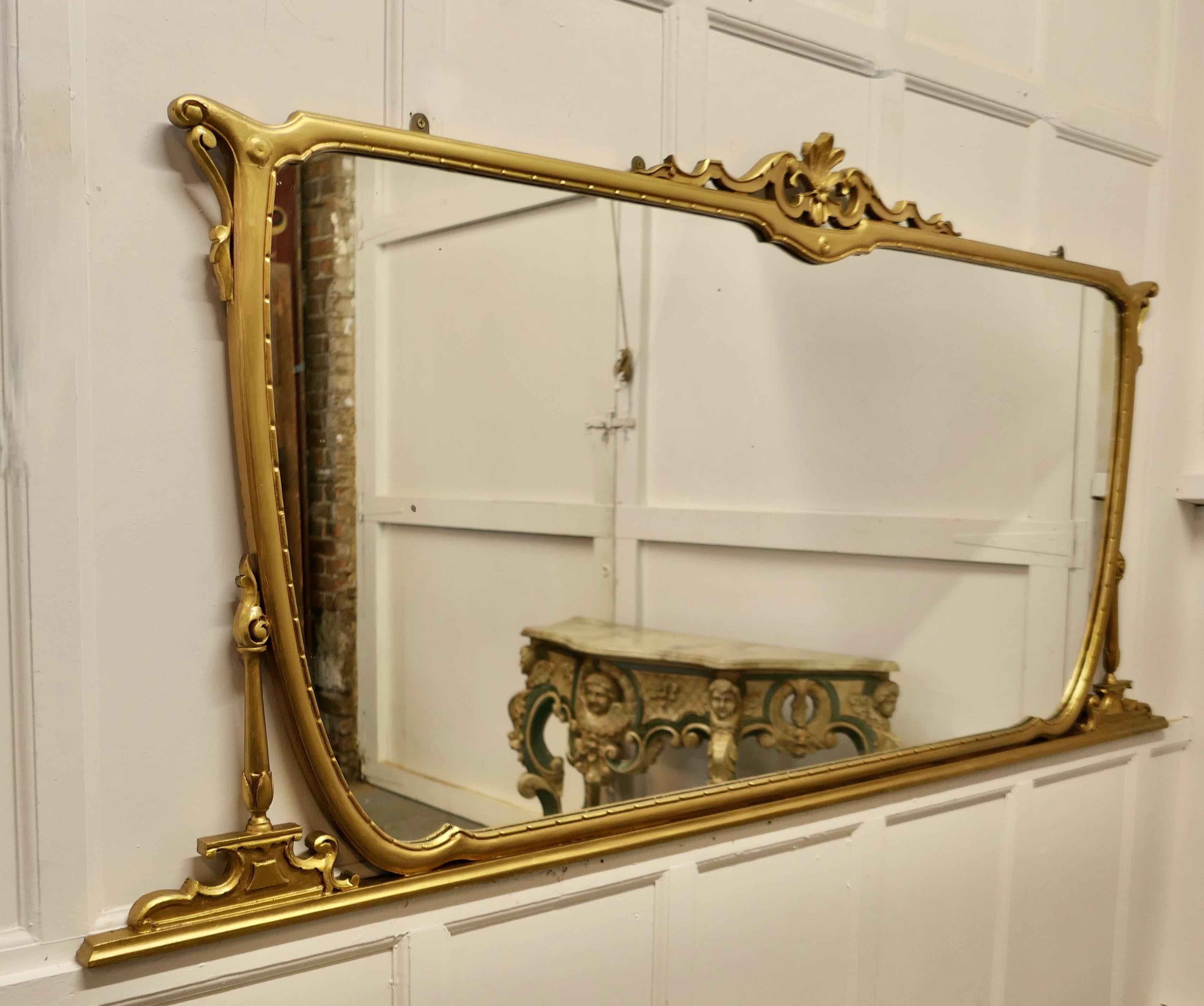 A very large Art Nouveau gilt over mantle mirror 

This mirror has a beautiful stylish Gold Frame it is decorated along the top sides and bottom 
 The long gilt frame is in good sound condition, and the looking glass too is in excellent