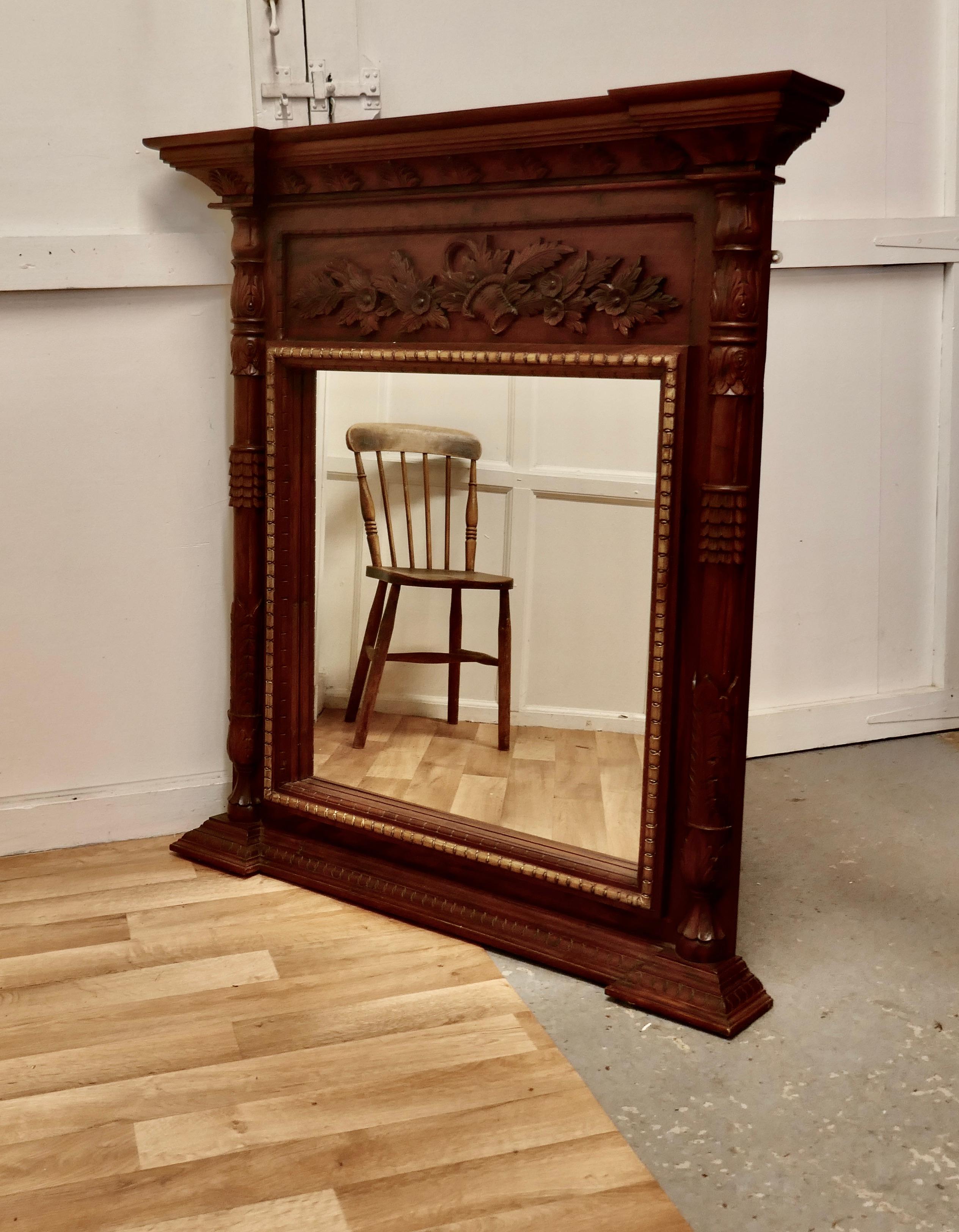A very large carved fruitwood overmantel or wall mirror.

This is a very large mirror the frame has a carved decoration at the top, a gilded border around the glass. It has a turned column at each side and a deep cornice matching the stepped base