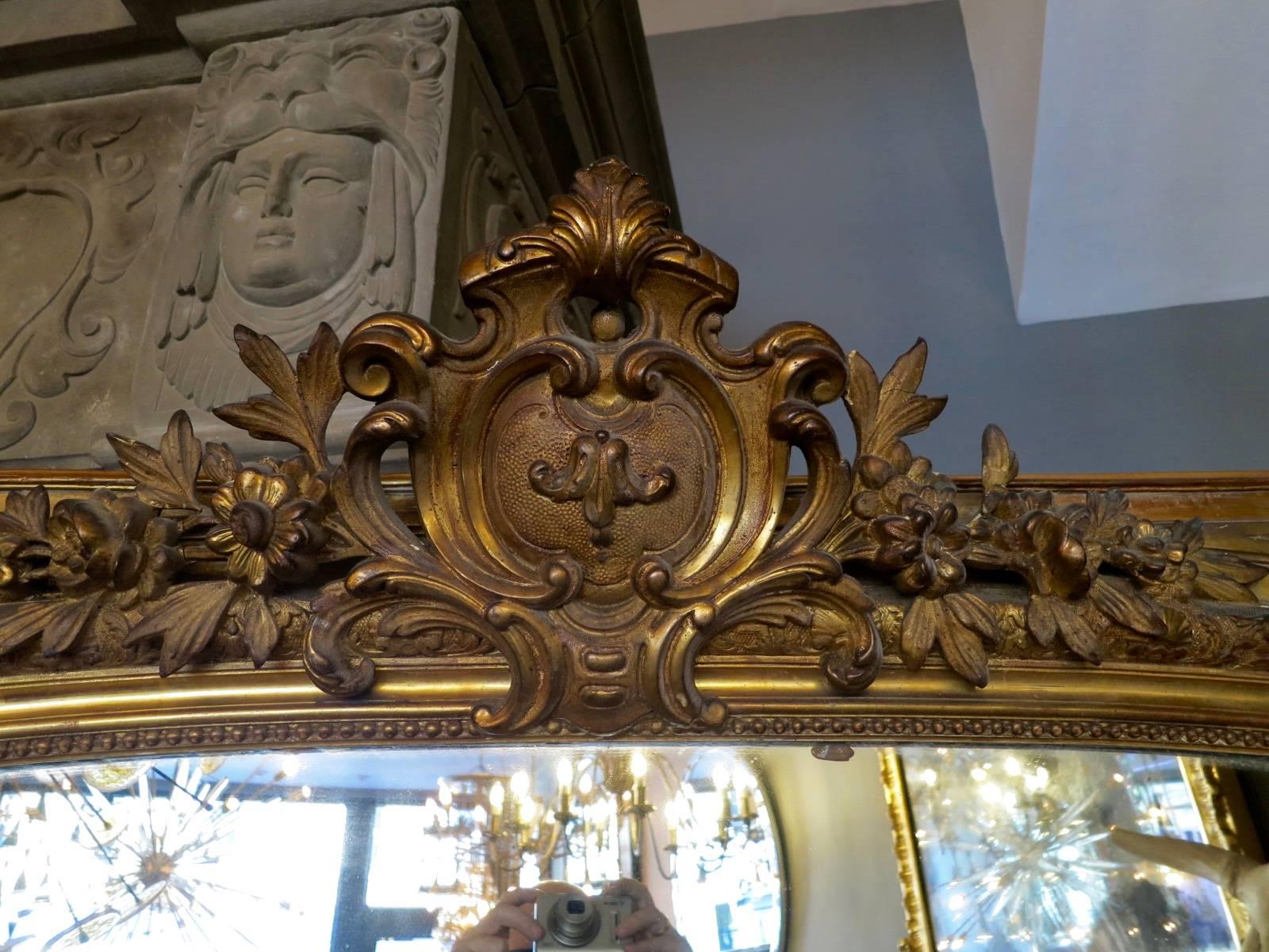 A large antique 19th century French overmantel mirror, with original plate mirror decorative frame and large central cartouche.
