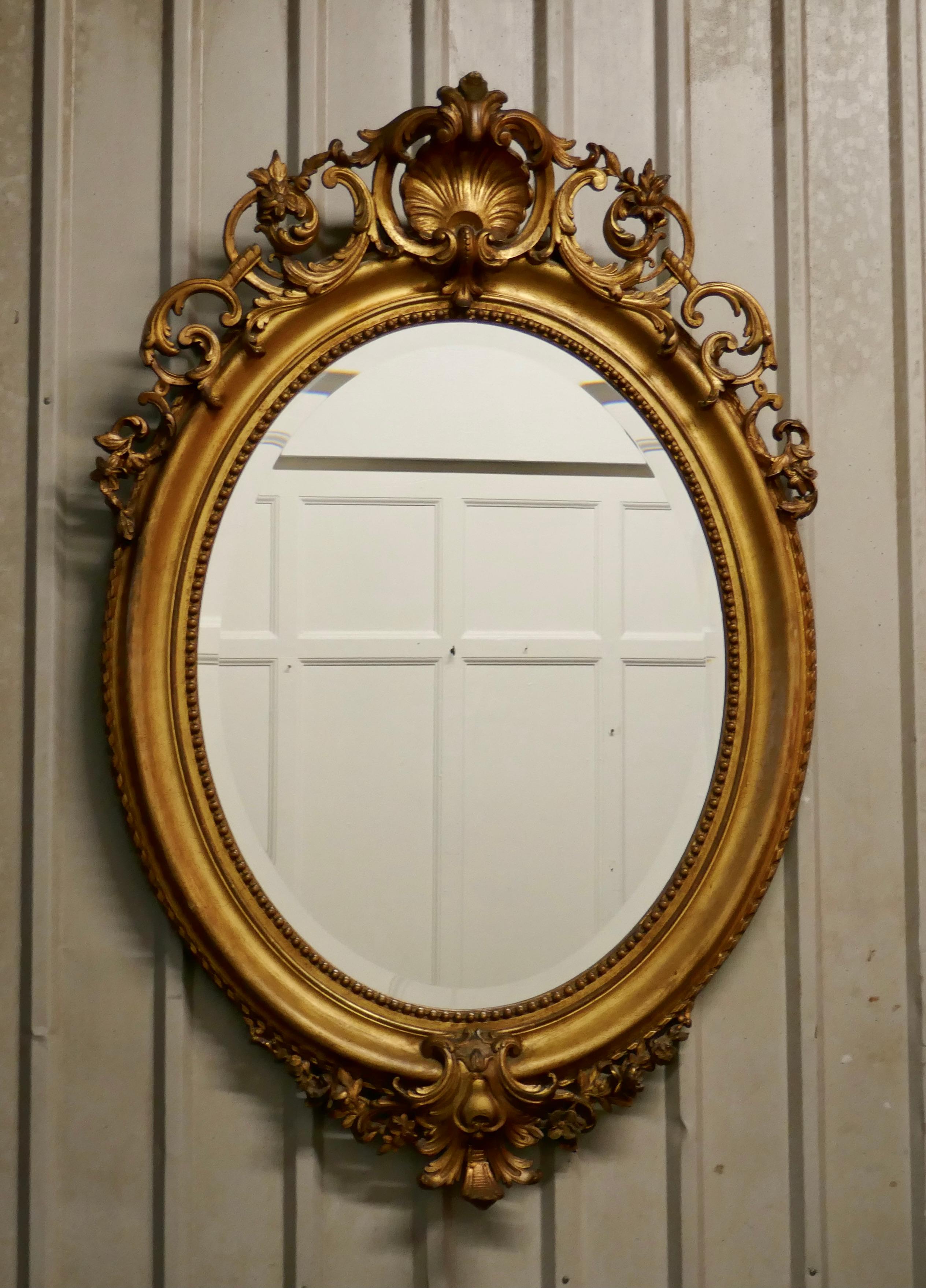 A very large French Rococo oval gilt wall mirror

The mirror has an exquisite gilt frame in the Rococo style, it is elaborately decorated with shells, swags and leaves with a neat rope edge
The large age darkened oval frame is made in gesso and