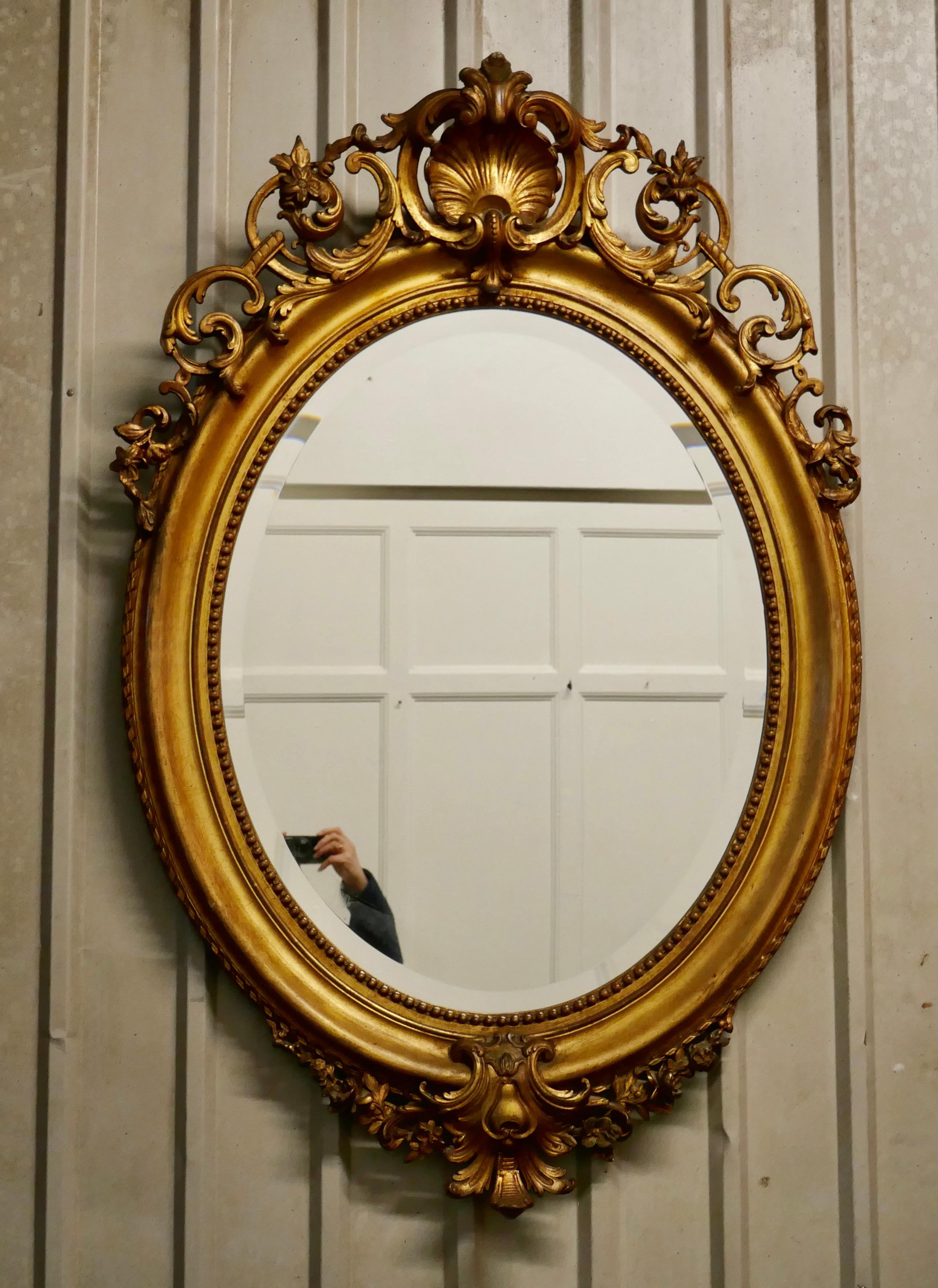 Très grand miroir mural ovale doré de style rococo français

Le miroir a un cadre doré exquis de style rococo, il est décoré de manière élaborée avec des coquillages, des guirlandes et des feuilles avec un bord en corde soigné.
Le grand cadre ovale,