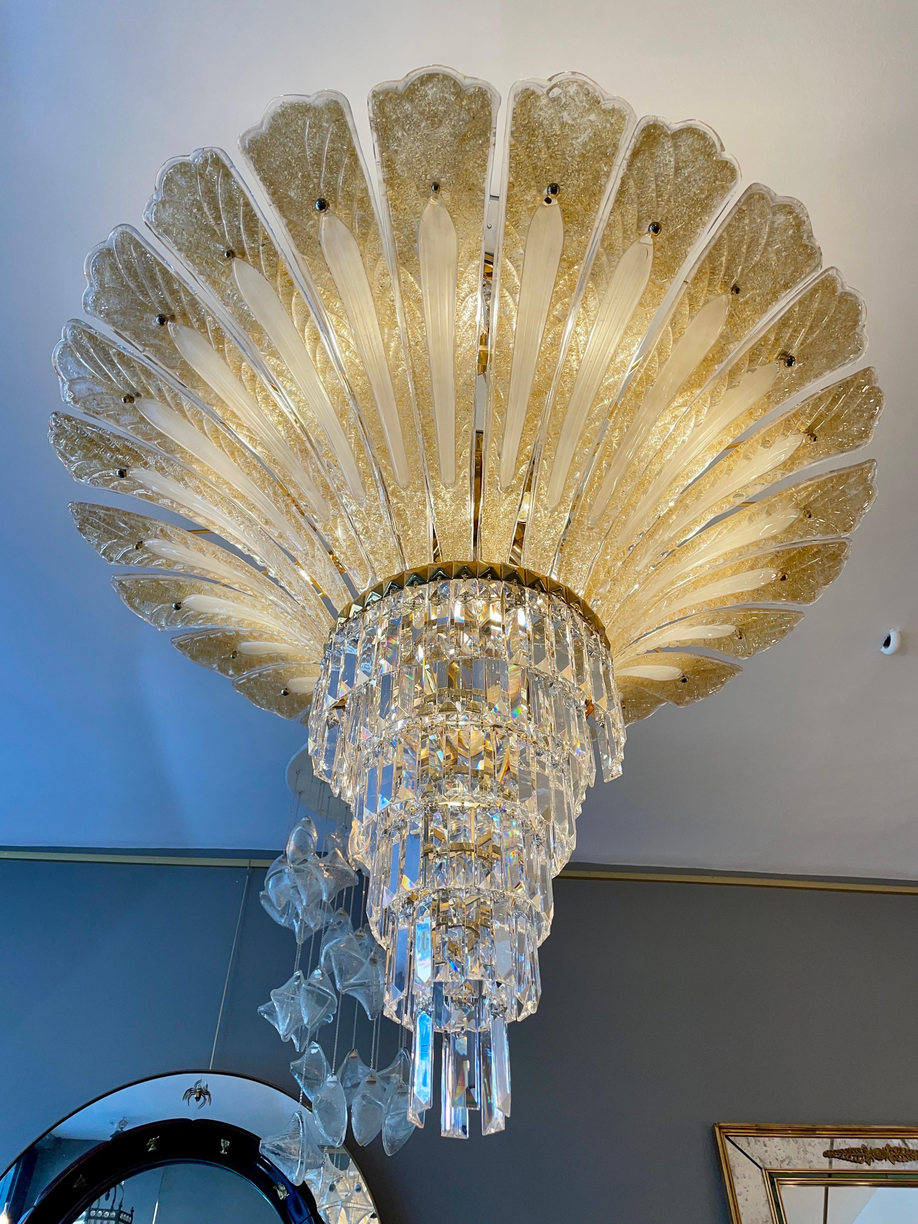 A very large flamboyant Murano palm leaf chandelier. The gilt frame supporting the 24 Carat gold flecked Murano glass leafs, with a tiered crystal bottom. The ceiling supports of round crystal balls within gilt bars. A very unusual and rather