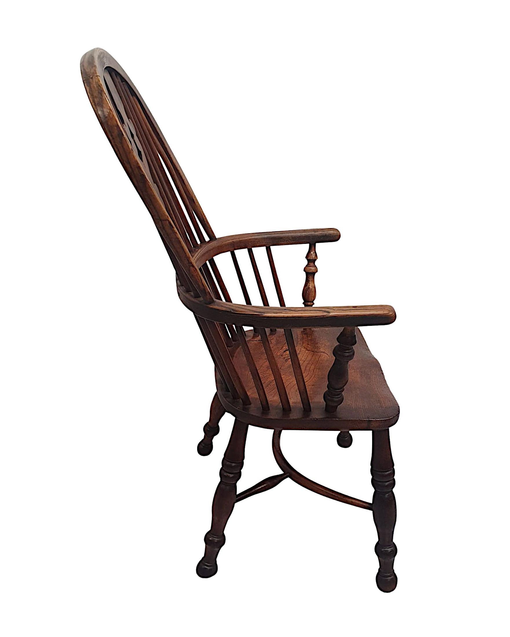 A very rare and fine 19th century Windsor armchair, stunningly hand carved and of exceptional quality with richly patinated woods comprising of ash and elm. The high hoop back with shaped, central fret cut back splat with decorative scroll motif