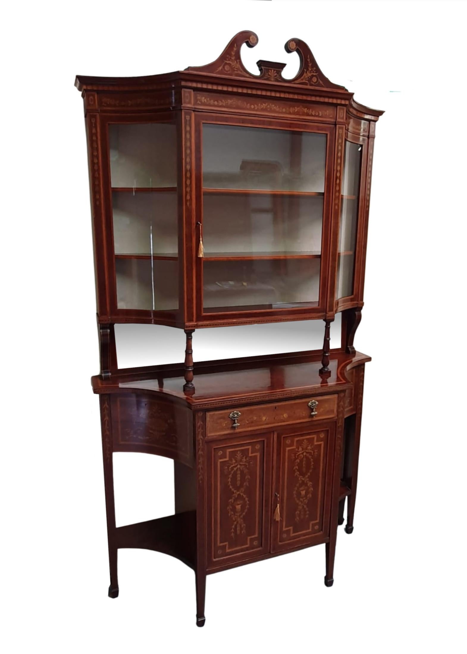 A rare and very fine Edwardian mahogany display case by 'Edward and Roberts'. Inlaid with intricate floral marquetry throughout depicting swags, garlands, flowerheads and trailing bell flowers. The moulded stepped broken swan neck pediment raised