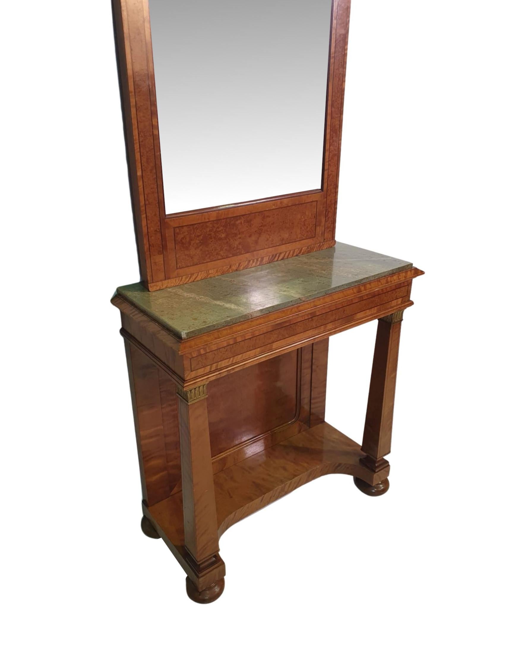 Une très rare table console en bois de satin du 19ème siècle, d'une hauteur étonnante et de proportions sveltes, incrustée de lignes et de bandes croisées. La corniche moulurée et étagée surmonte un beau panneau en verre églomisé à motifs