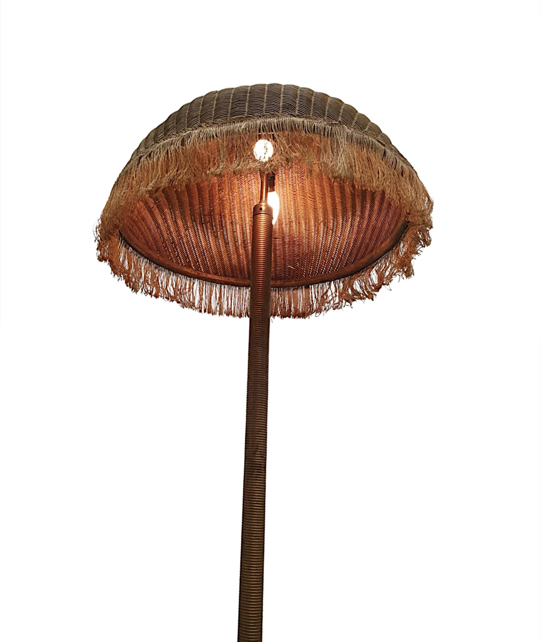 A very rare original 1930's Lloyd Loom hand weaved wicker rattan wood stand up floor lamp of fabulous quality and with a gorgeous patina.   The stunningly crafted weaved wicker shade of circular form with decorative fabric tassels is surmounted with