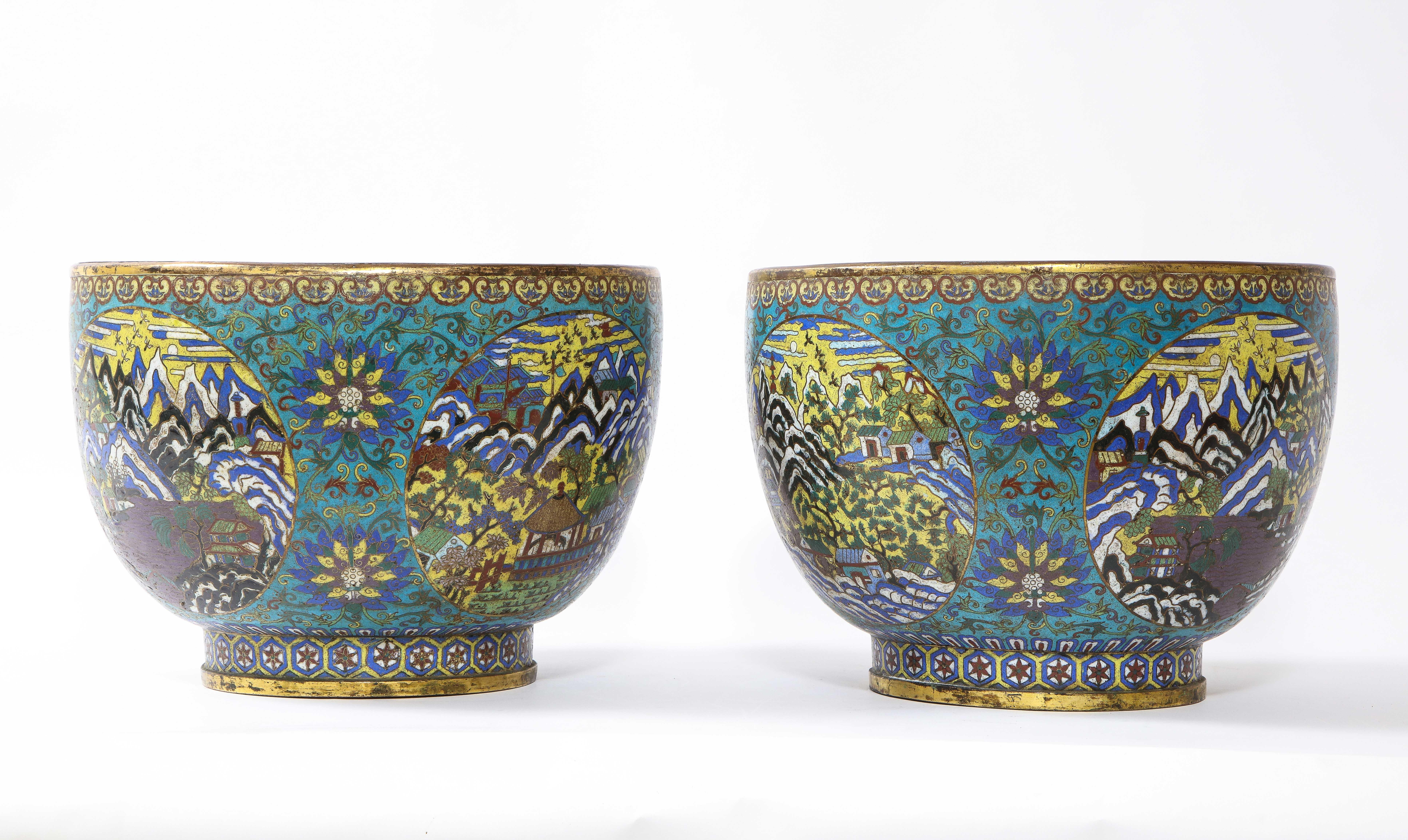 Ein extrem seltenes Paar chinesischer Cloisonné-Pflanzgefäße aus der Kangxi-Zeit mit Landschaftsszene. Diese Gefäße haben eine tiefe Schalenform mit vertieften, vergoldeten Rändern und kurzen, leicht taillierten Fußringen. Ihre Oberflächen sind